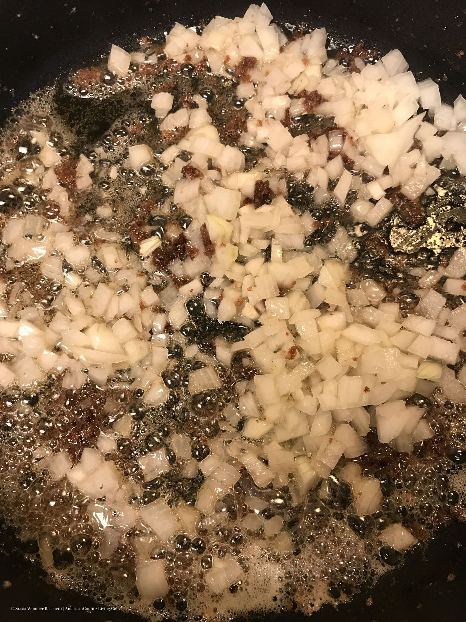 Diced onions sauteing in a cast iron skillet with browned meat drippings.