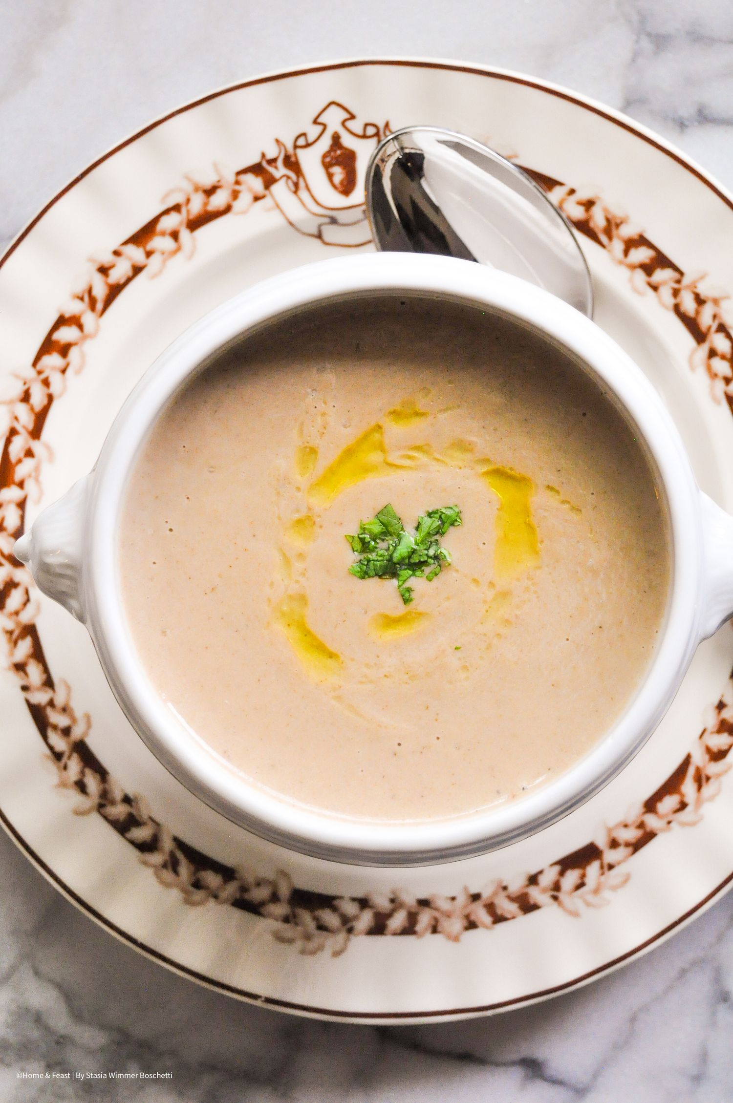 Creamy mushroom soup garnished with shredded cheese and fresh herbs served in elegant white bowls.