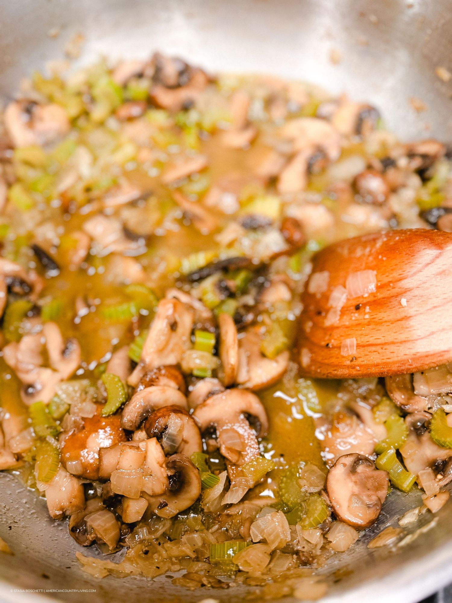 Sautéed mushrooms and leeks cooking in a skillet with a wooden spoon, creating a savory aromatic base.