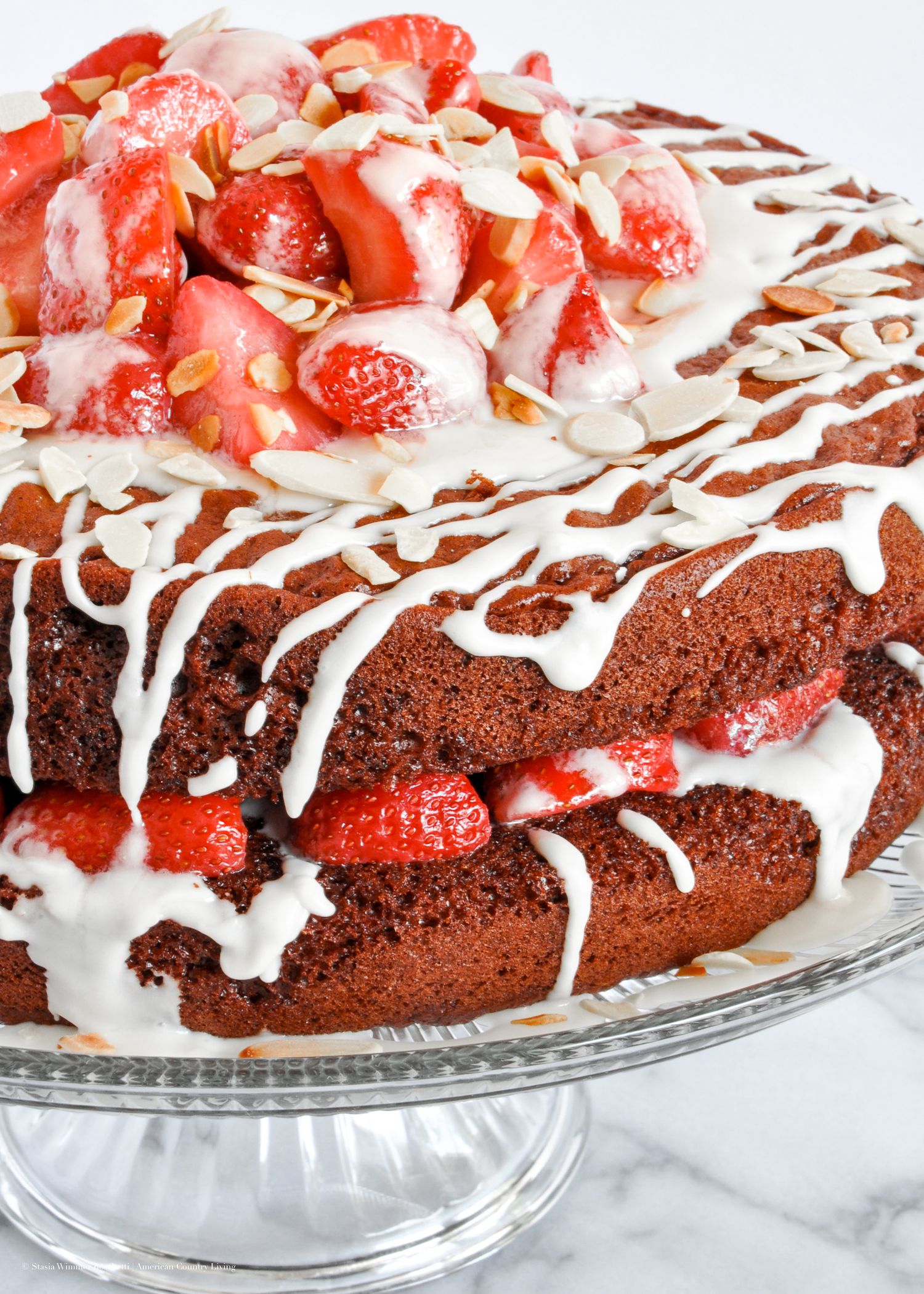 Chocolate trifle dessert topped with fresh strawberries, white chocolate drizzle, and toasted almonds in a glass bowl.