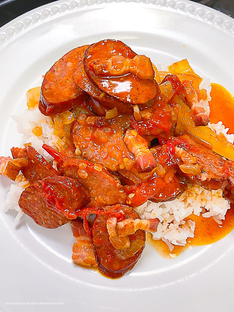 Sausage and vegetable dish served on a white plate with rich tomato sauce.