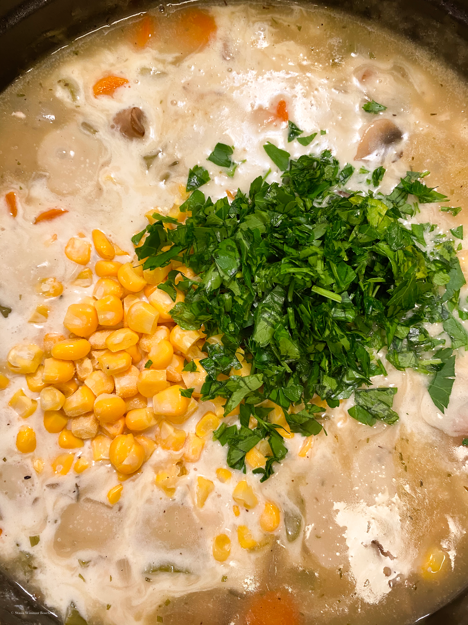 Creamy sauce with corn and fresh chopped parsley being added as garnish.