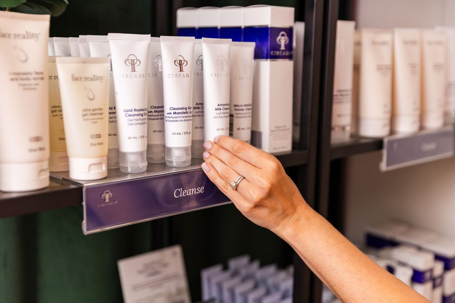 Hand reaching for skincare products displayed on retail shelf.