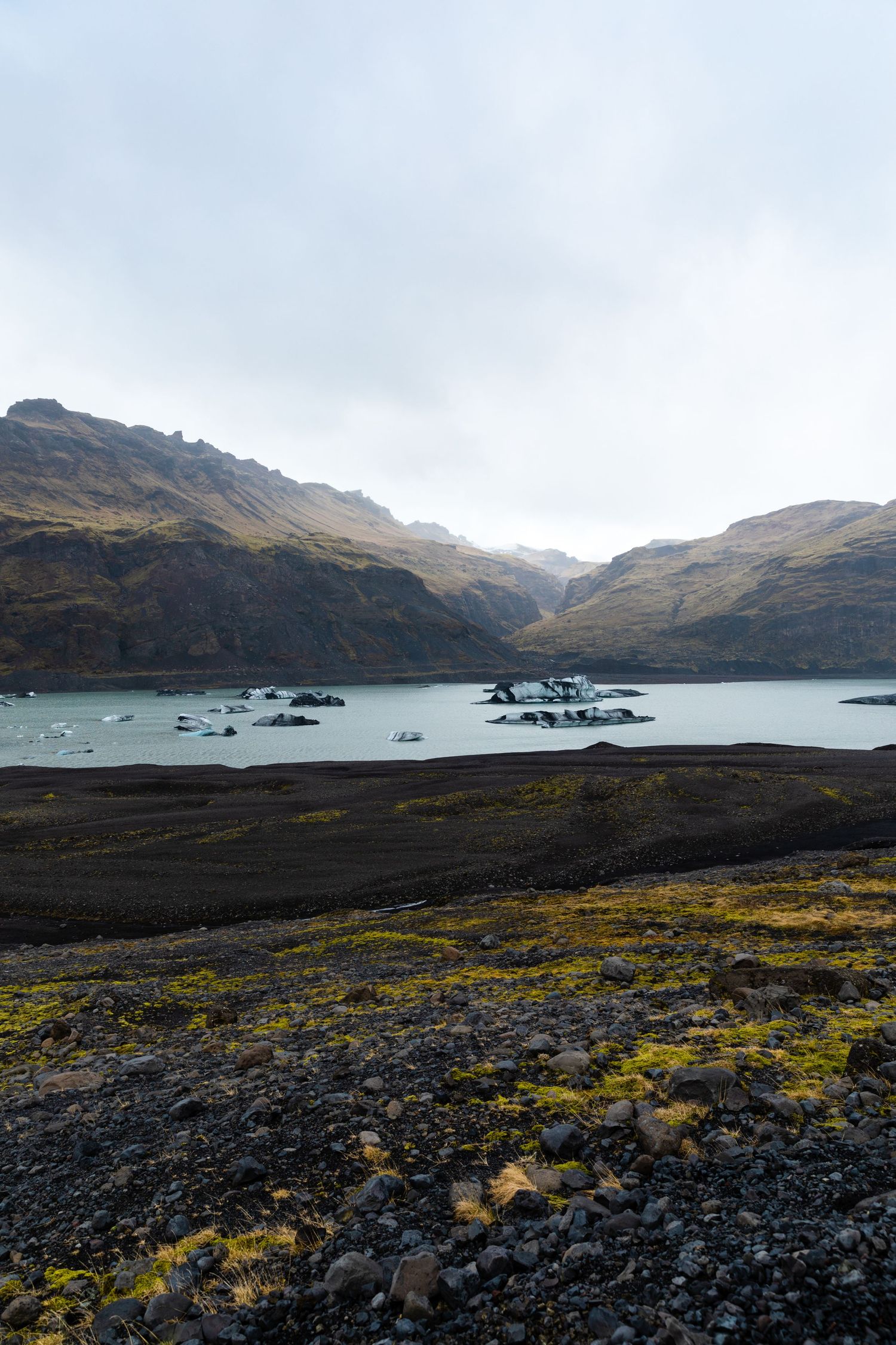 Rugged Icelandic landscape with mountains surrounding a tranquil lake dotted with small rocky islands.