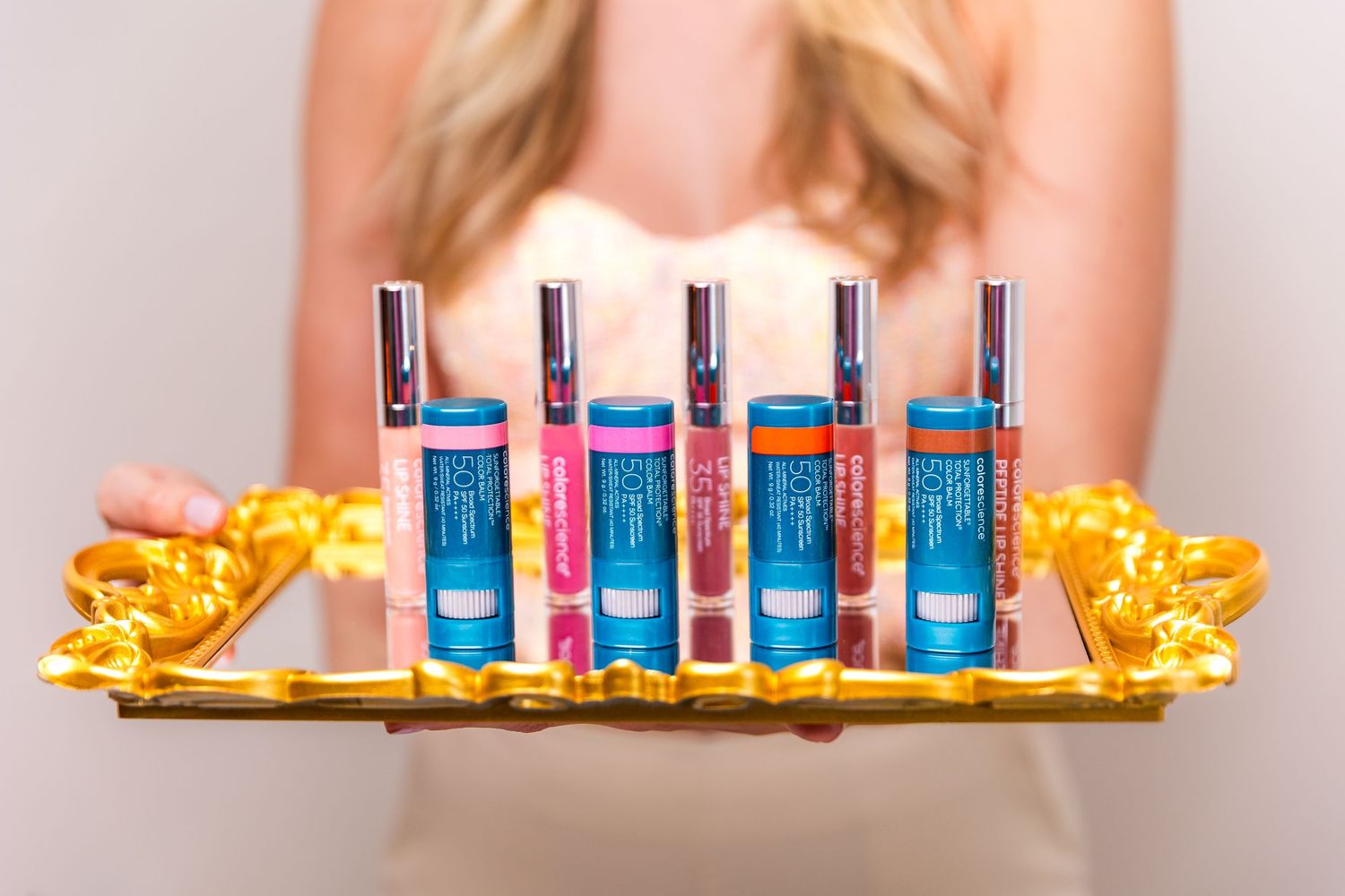 Row of blue cosmetic bottles displayed on golden tray with decorative elements.