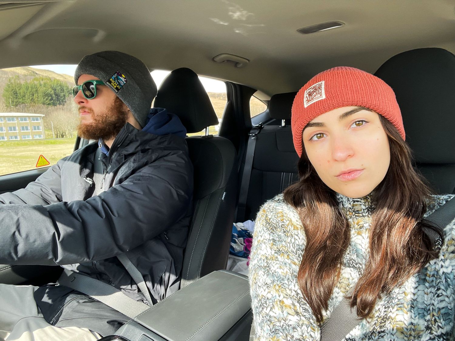 Two people taking selfie in car during road trip adventure.