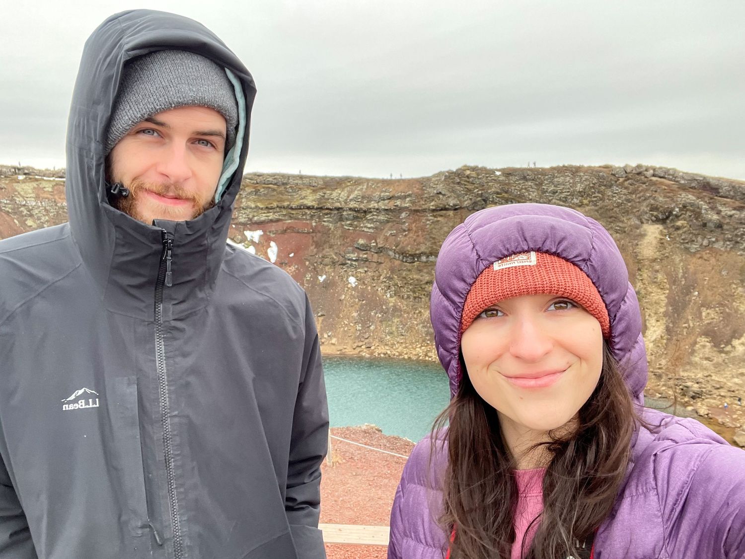 Two people in winter gear smiling against rocky natural backdrop.