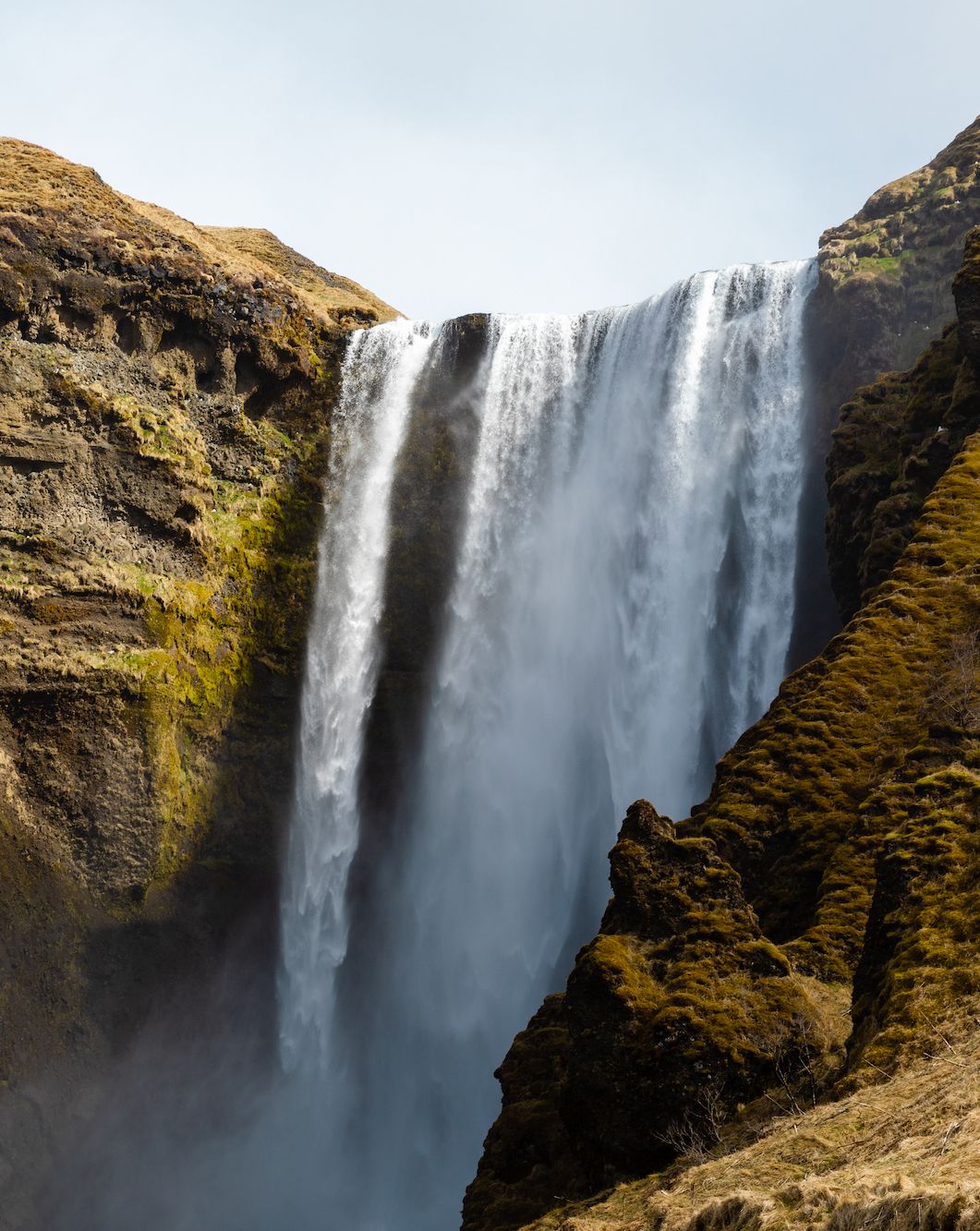 Majestic waterfall cascades down moss-covered cliffs in the Icelandic highlands.