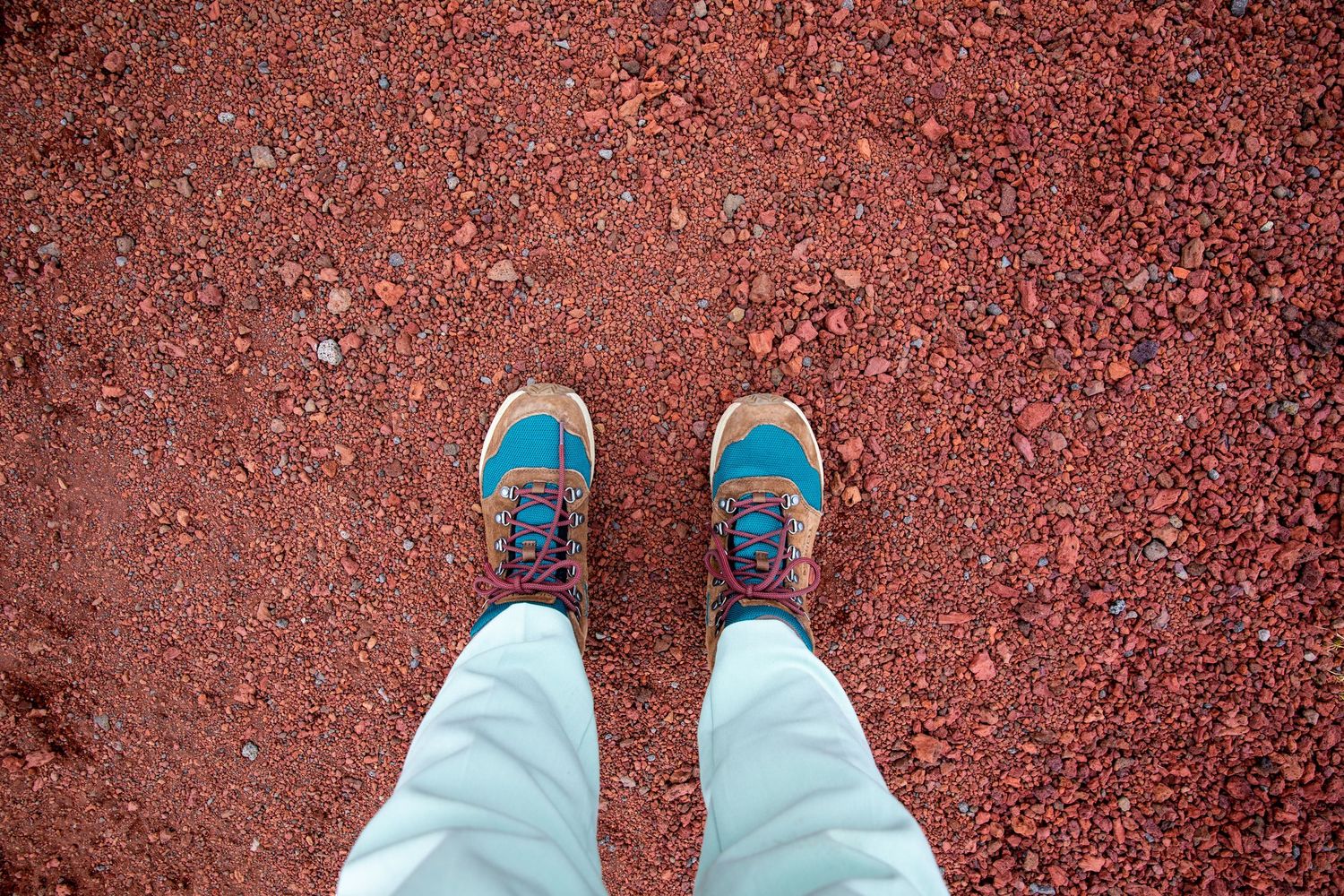 Blue Merrell shoes on red ground shown from first-person perspective.