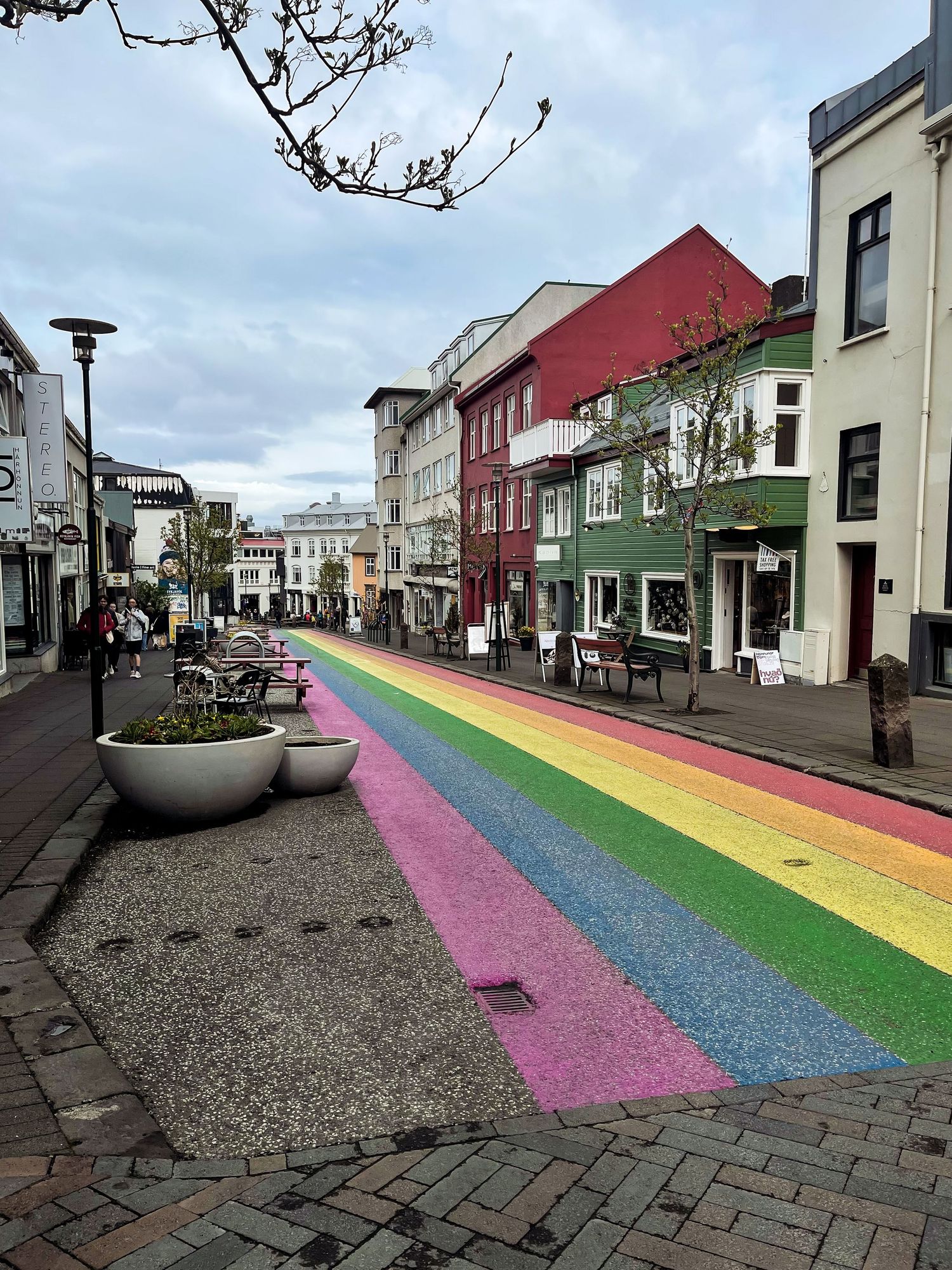 Colorful rainbow-painted street in a quaint town with historic buildings and shops.
