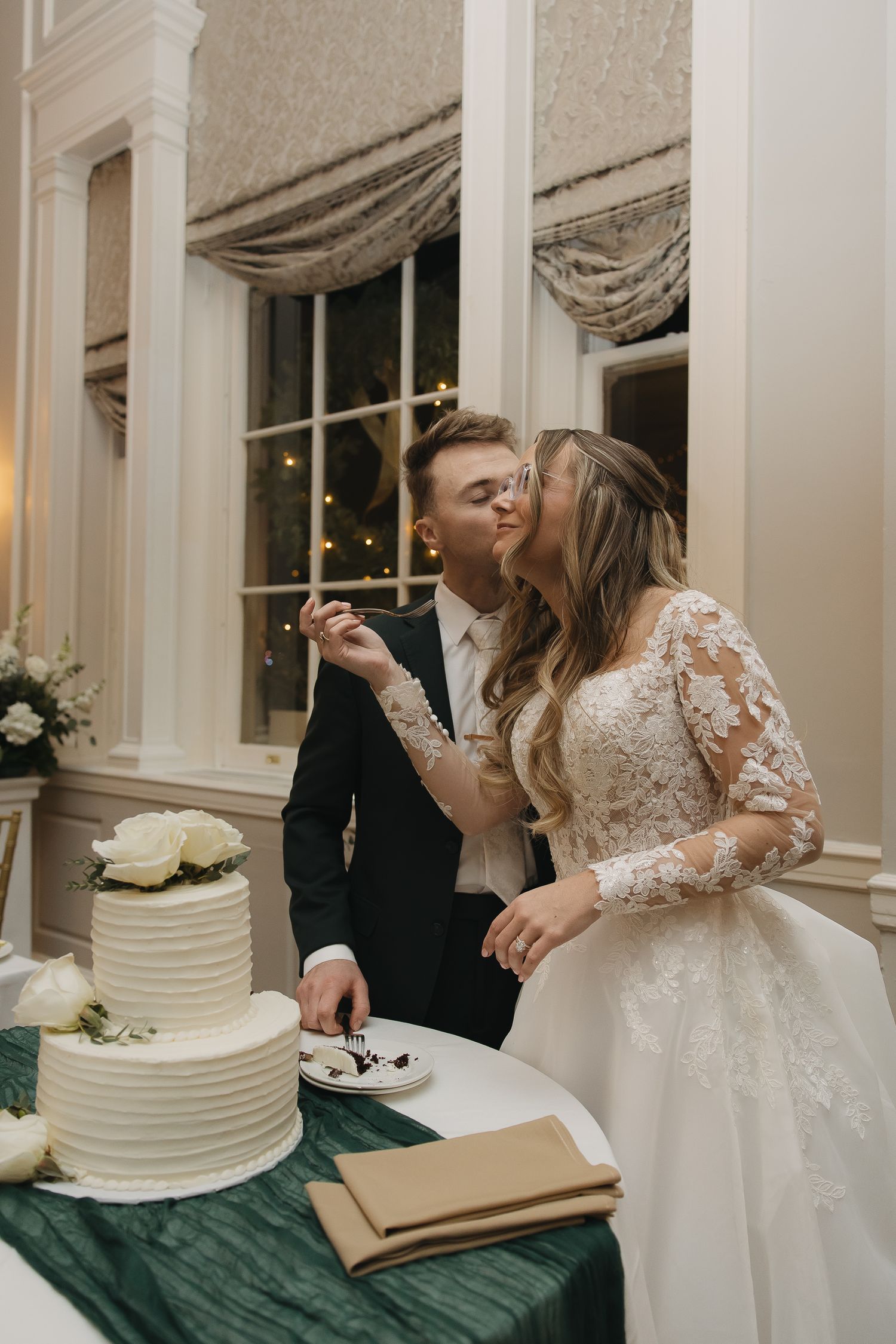 couple kissing while trying their wedding cake