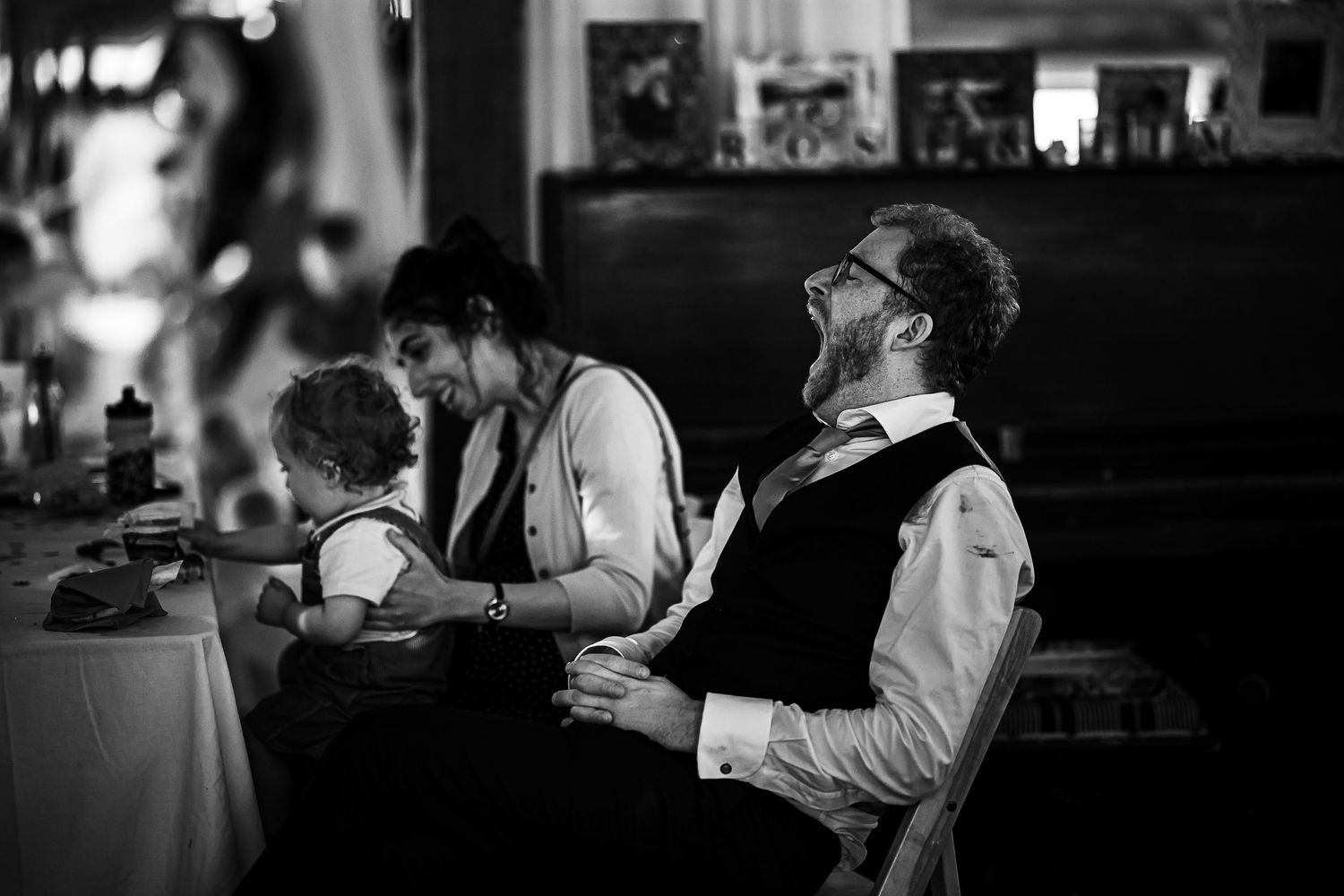 Black and white image of guests enjoying themselves at a social gathering indoors.