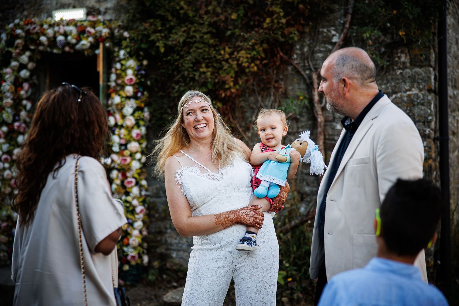 A joyful outdoor wedding ceremony scene with floral arch backdrop.