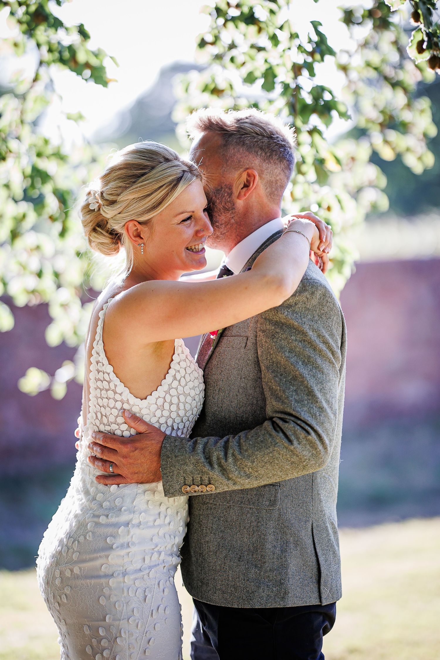 Intimate outdoor portrait of newlyweds embracing in soft natural light.