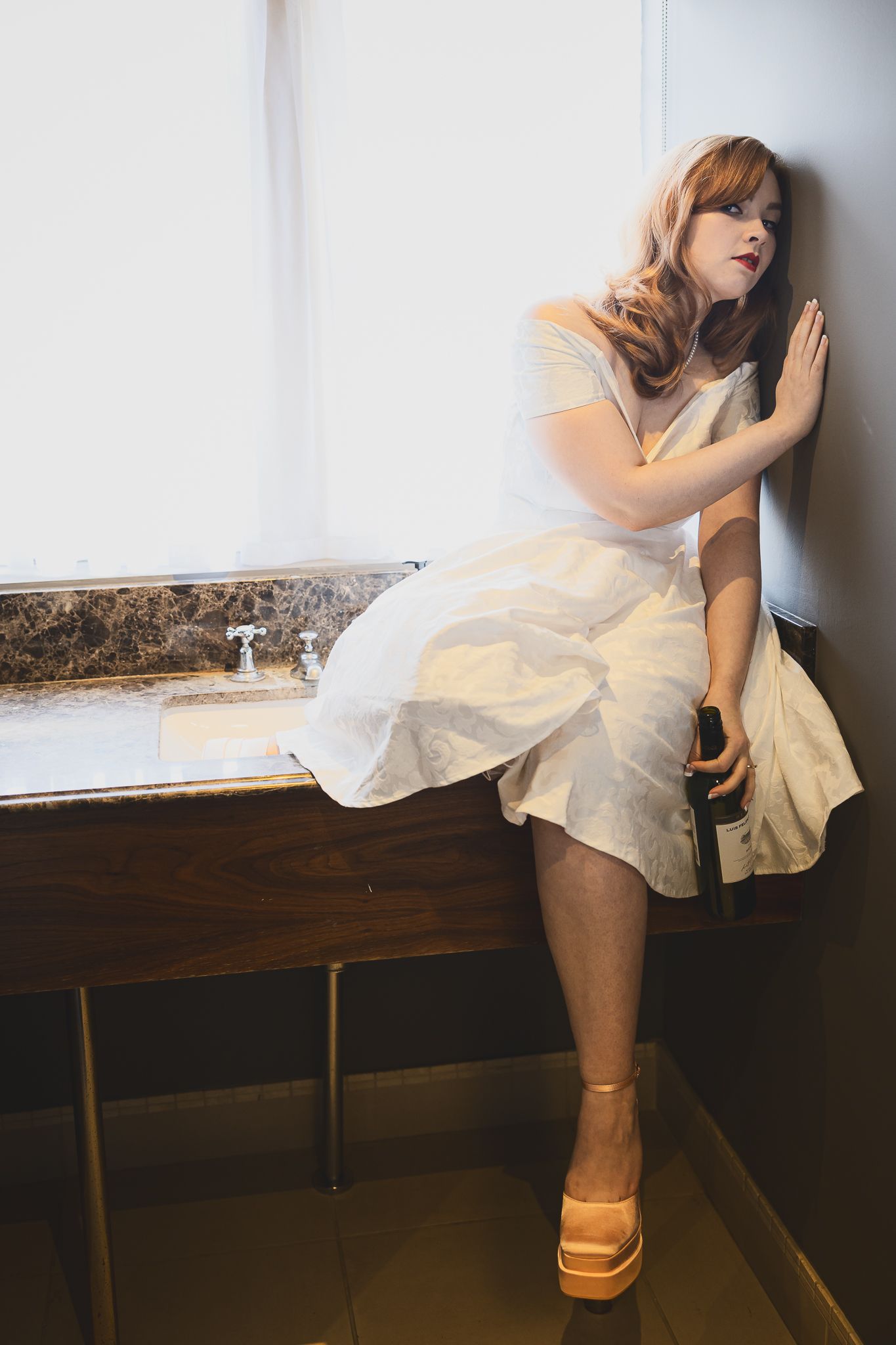 Bride in vintage dress leans against wall wearing platform sandals.