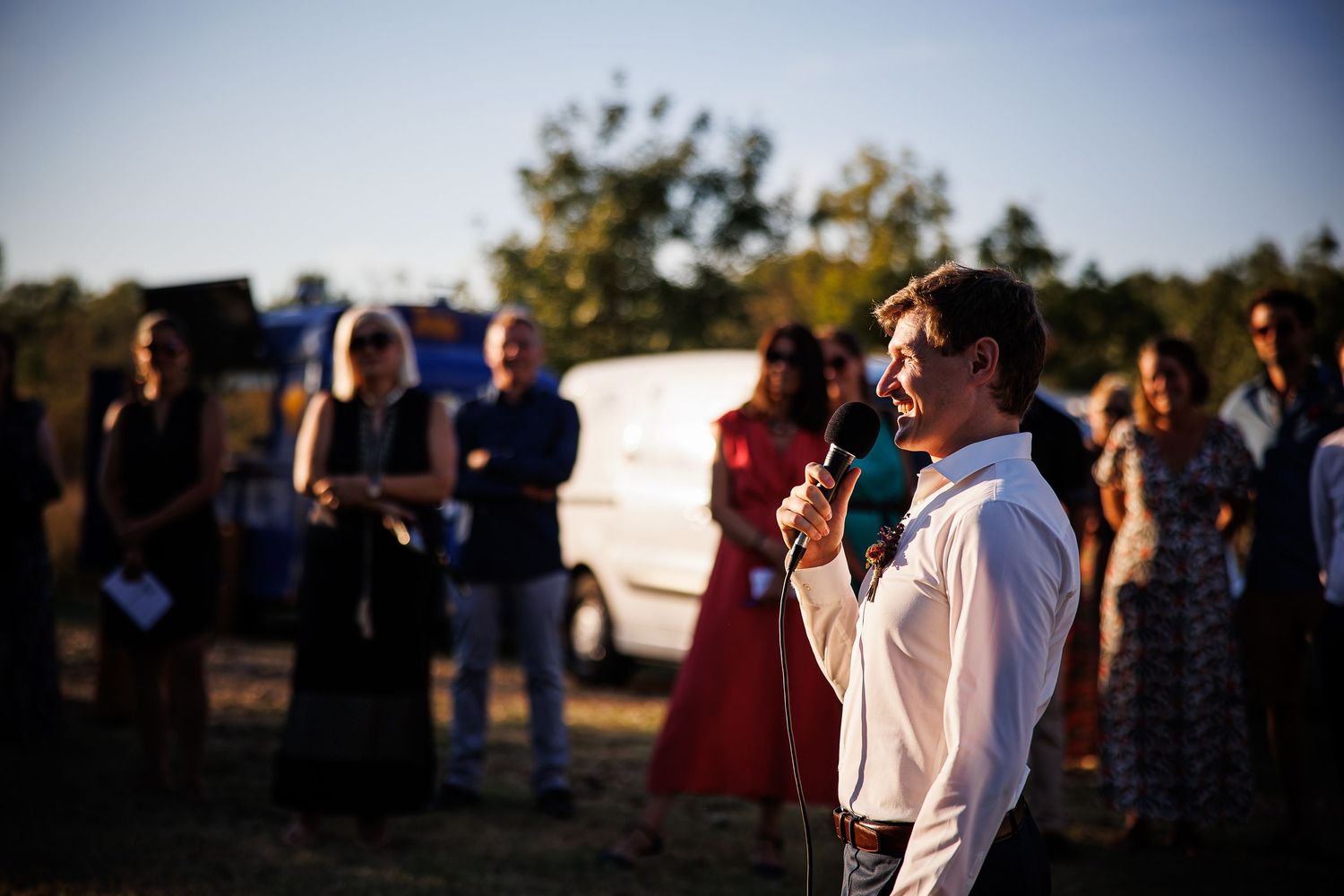 Speaker addresses crowd at outdoor gathering with microphone.