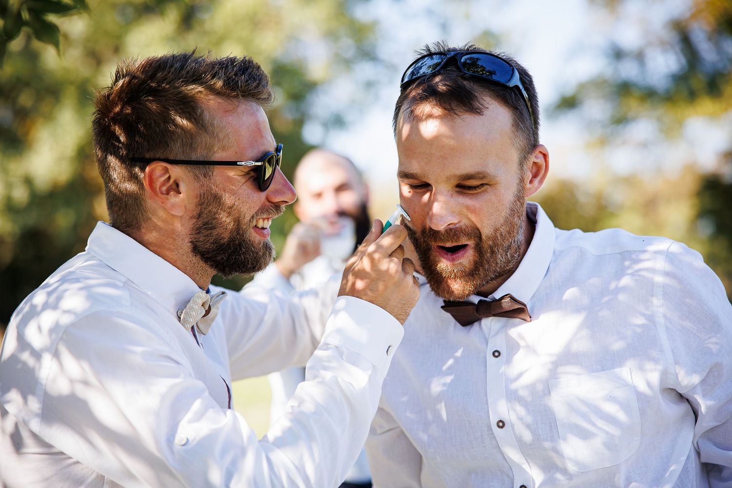 Two men in white dress shirts sharing a joyful moment at an outdoor event.