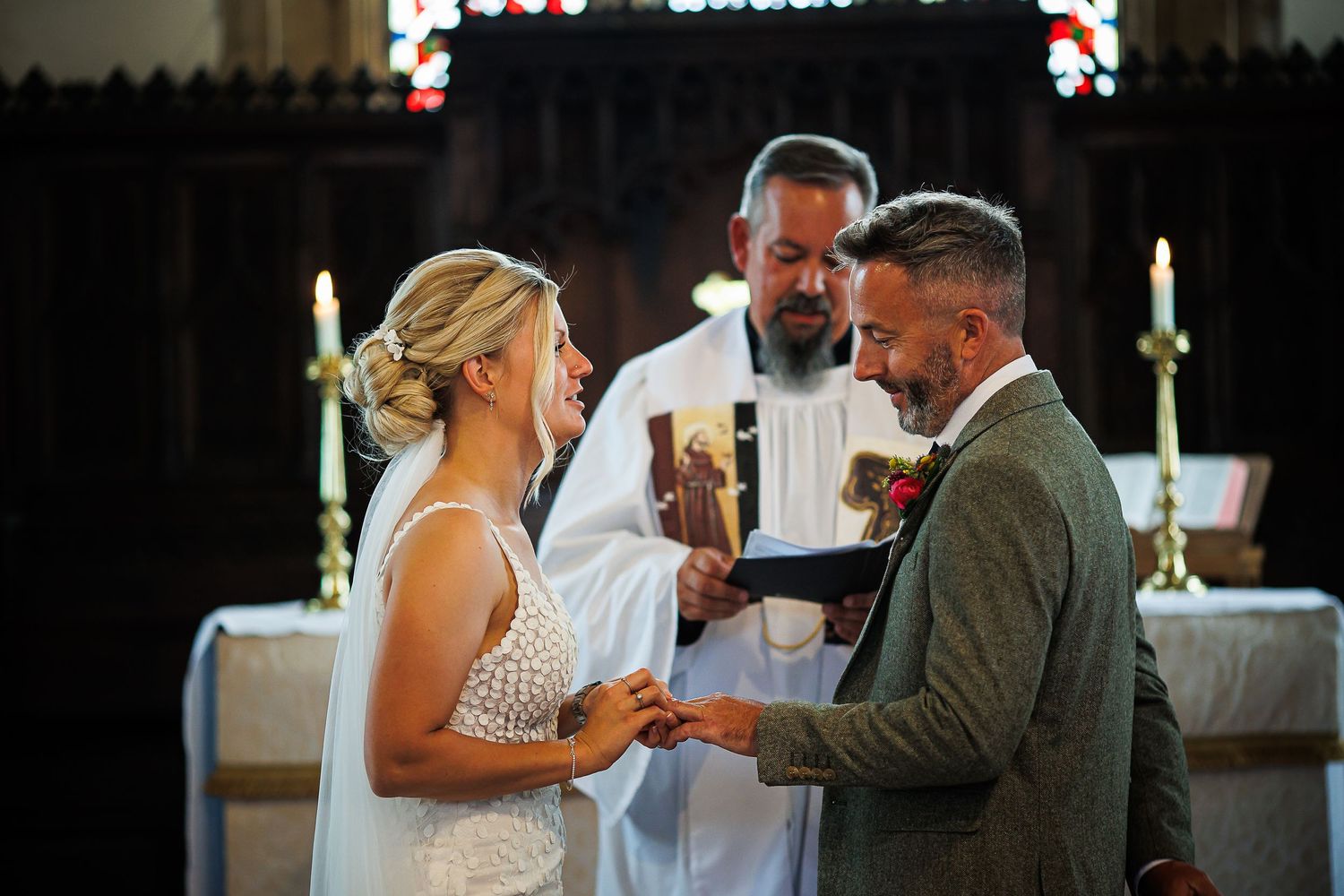 Traditional church wedding ceremony with couple exchanging rings at decorated altar.
