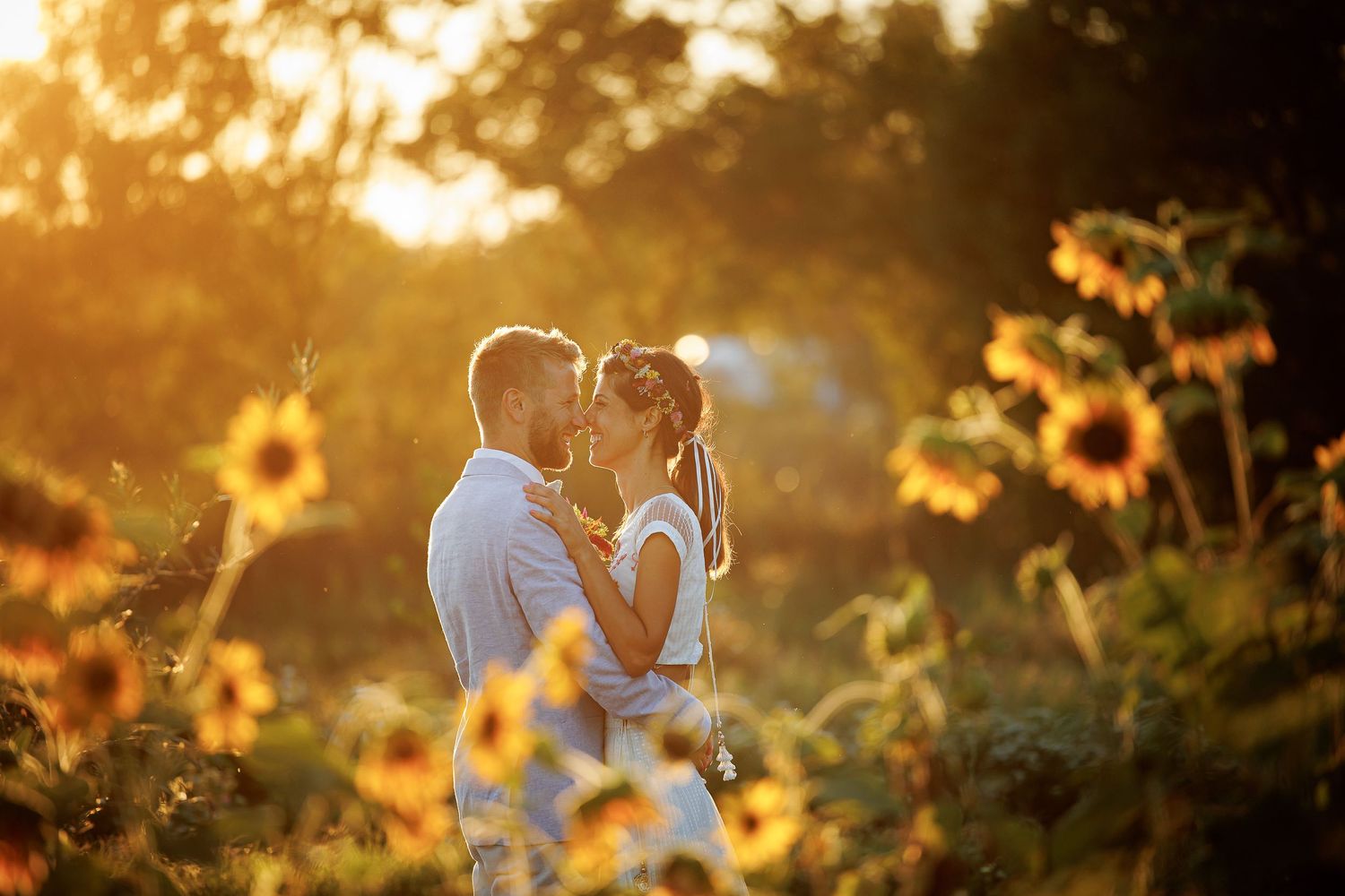 Romantic sunset portrait among blooming sunflowers in golden light.