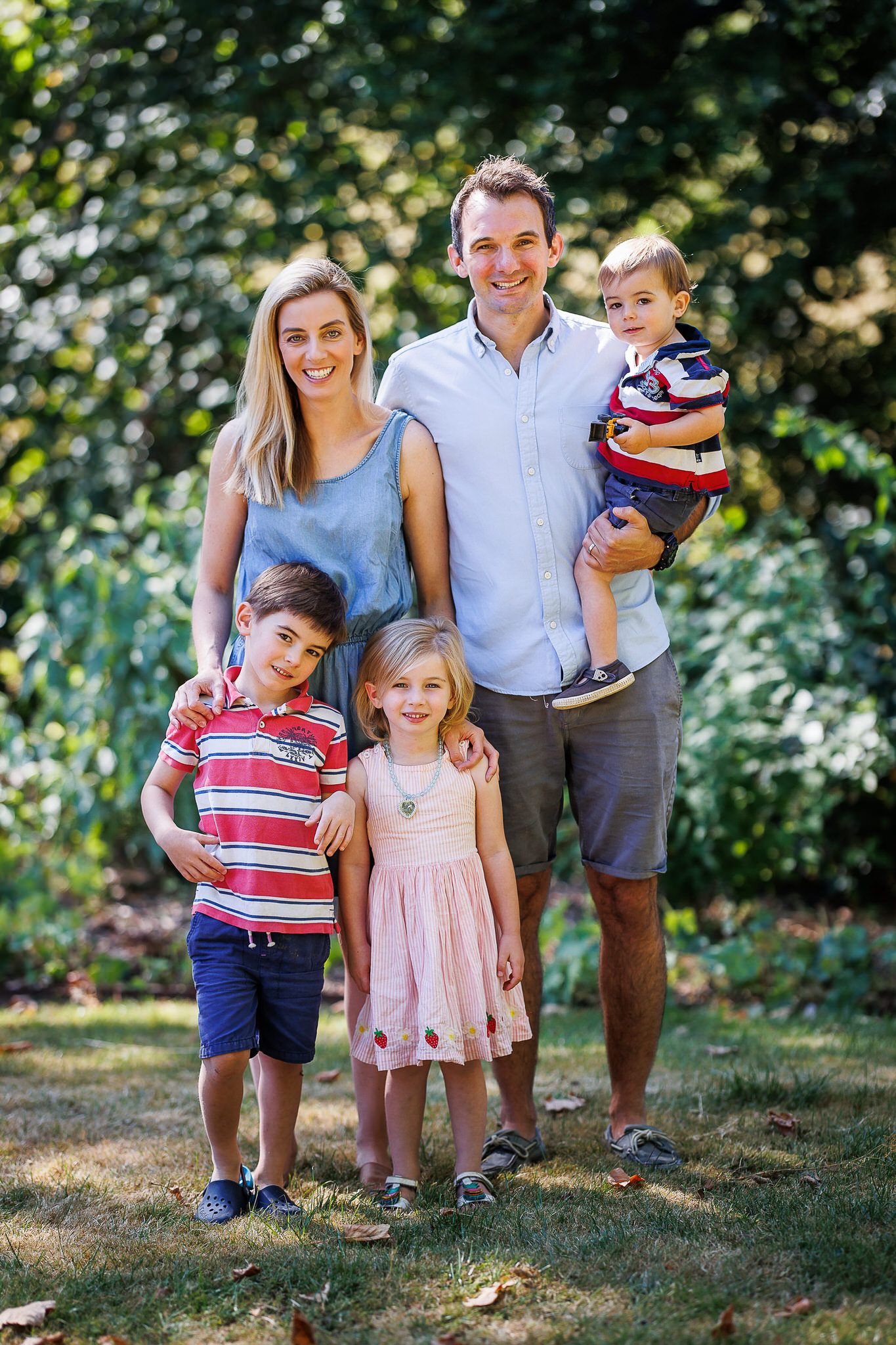 Happy family portrait of five people standing together in a summer garden.
