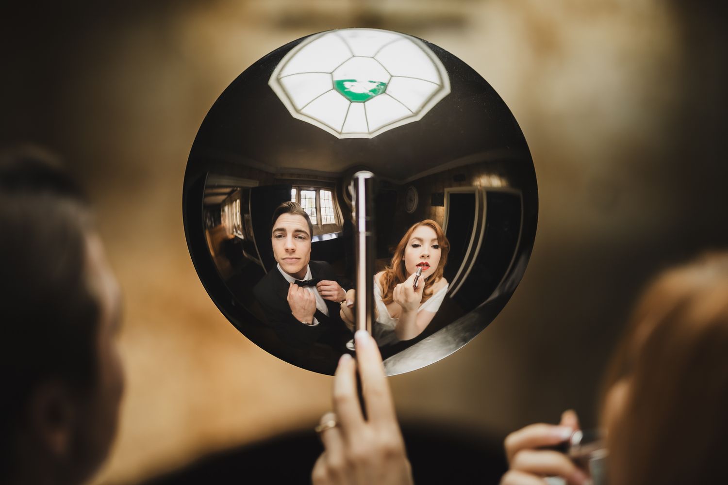 Creative vintage-style mirror reflection photo of couple getting ready for wedding in black and white tones.