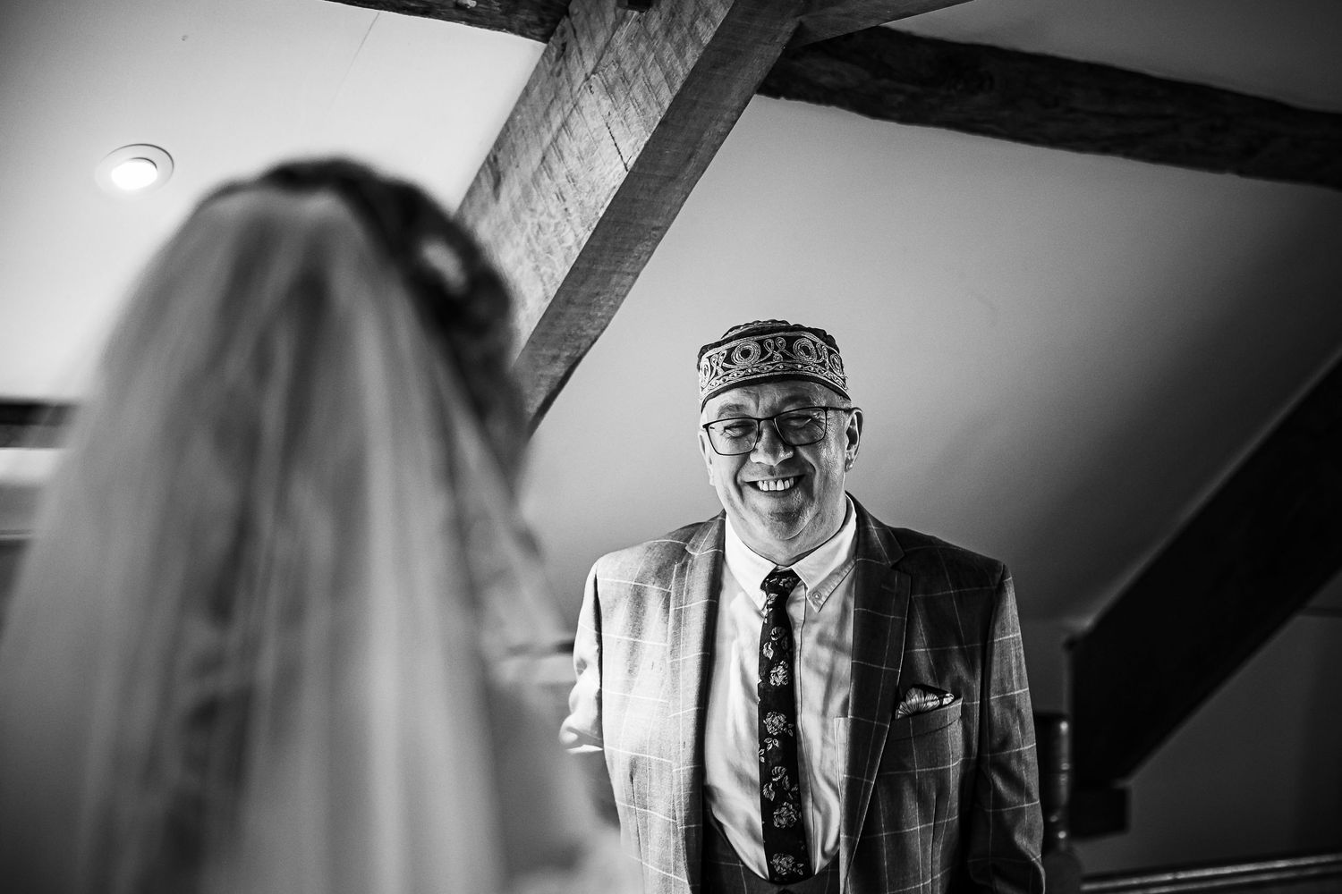 Black and white wedding moment captured under wooden beams.