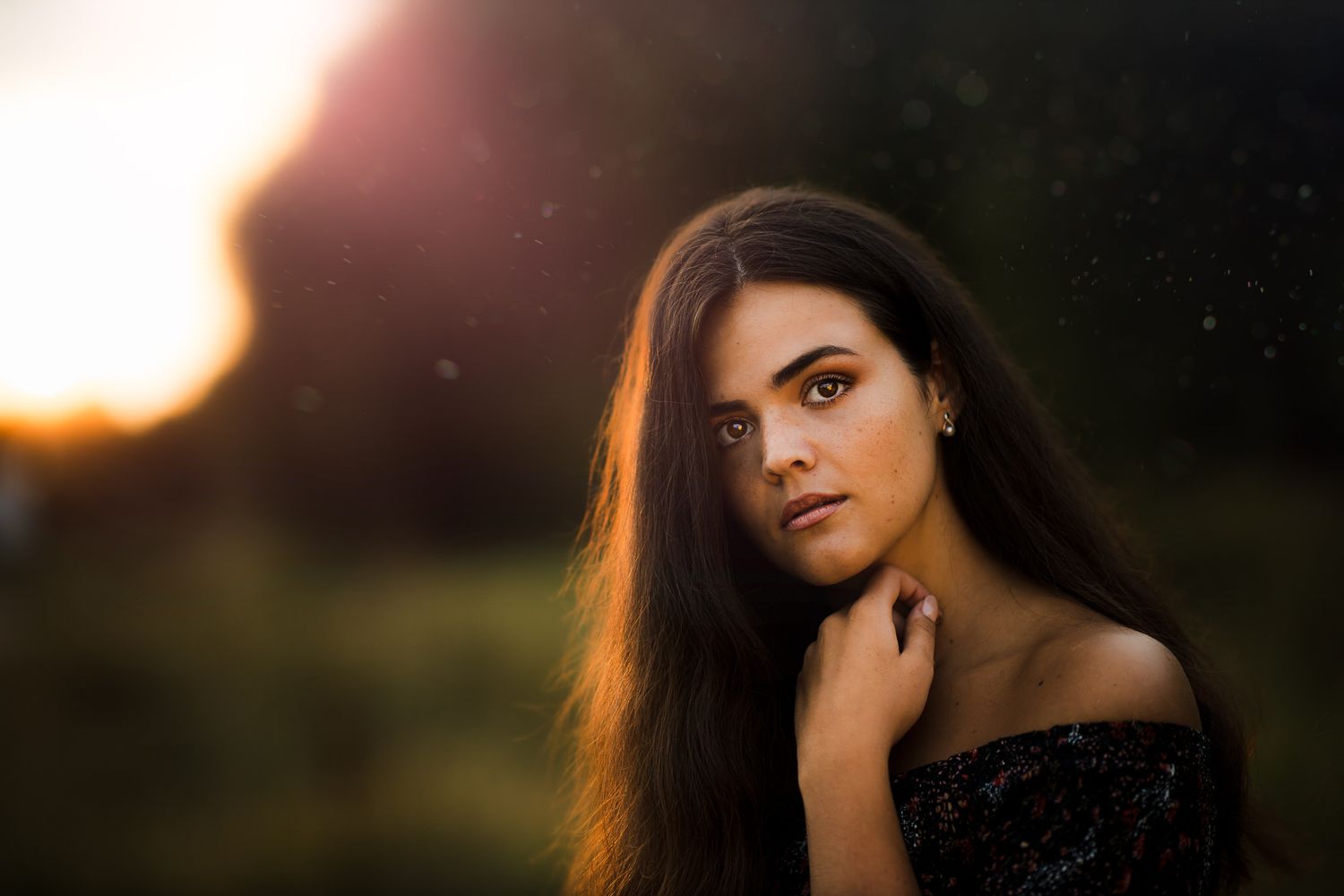 Dramatic portrait of a woman in black against a sunset background.