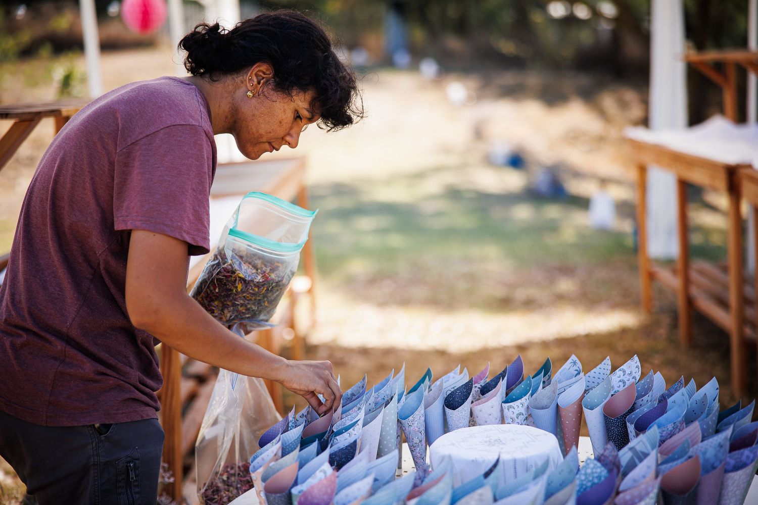 A person organizing rows of blue paper decorations at an outdoor craft table.