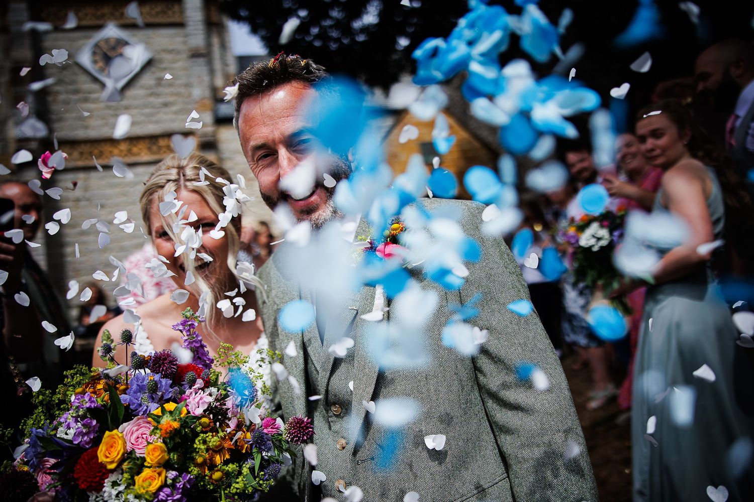 Artistic wedding photo with confetti and flowers creating dynamic motion blur effect.