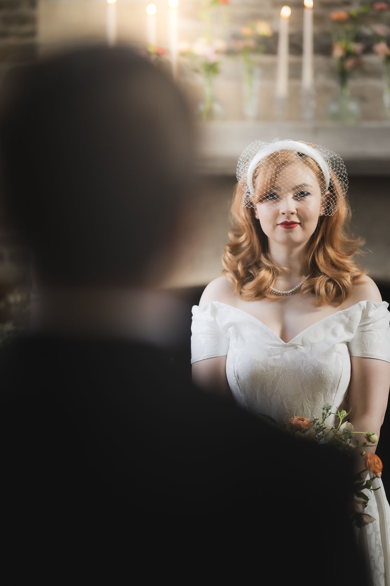 Bride in retro wedding dress seen through silhouette of groom in intimate ceremony setting.