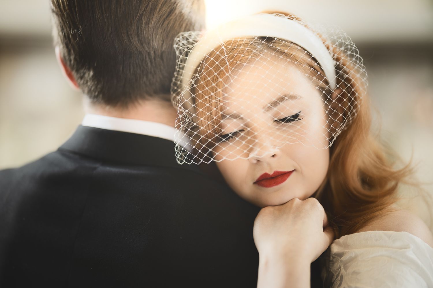 Intimate moment between newlyweds showing bride's vintage styling and red lipstick.
