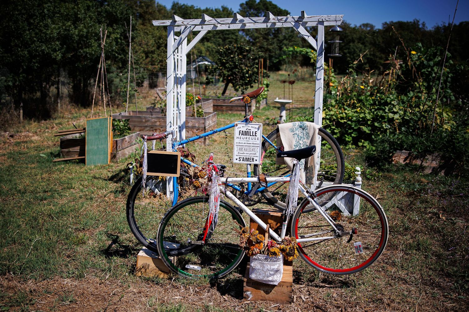 A vintage bicycle parked in front of a white garden arbor decorated with signs and decorations.