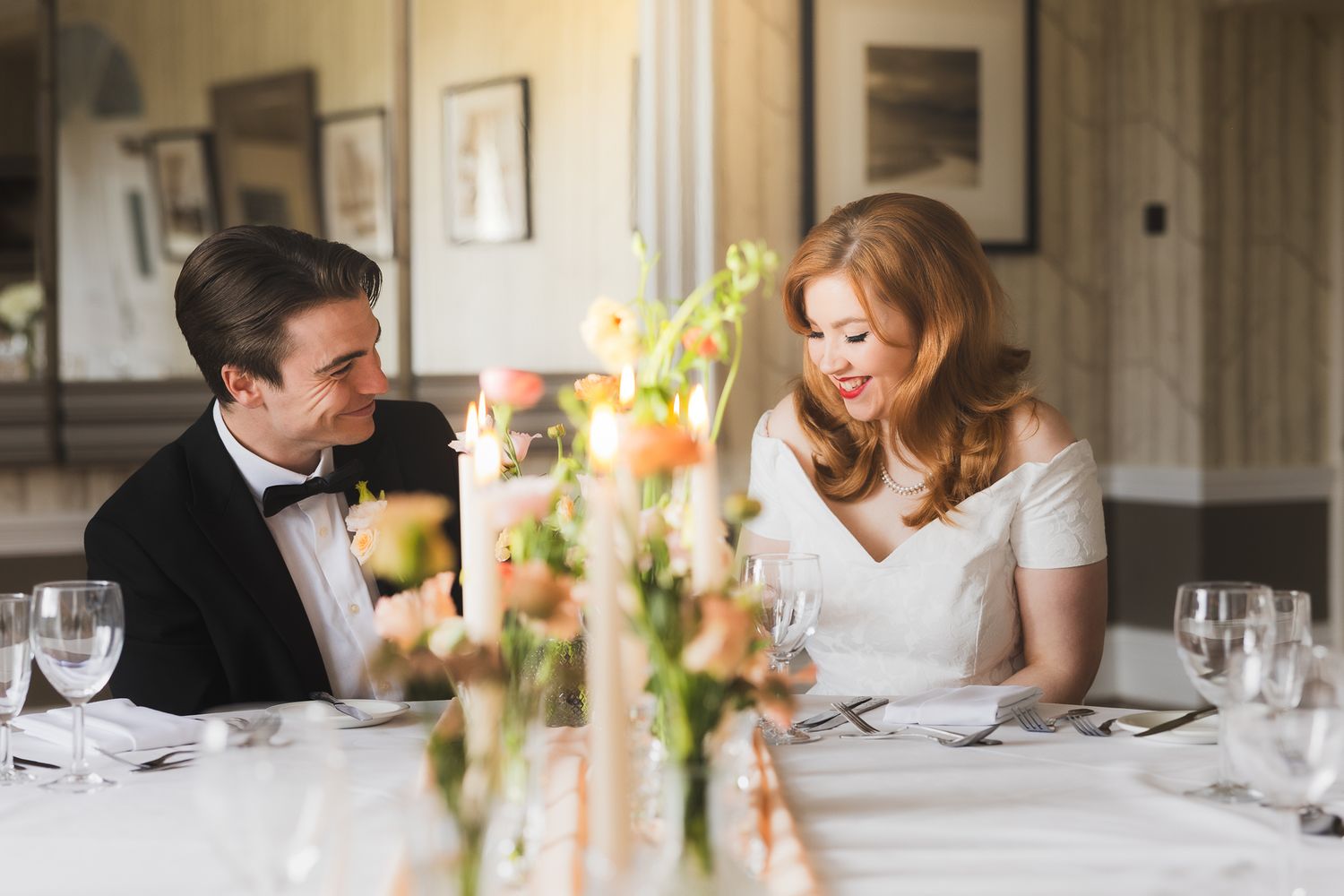 Couple shares intimate moment at elegant dining table with floral centerpiece.