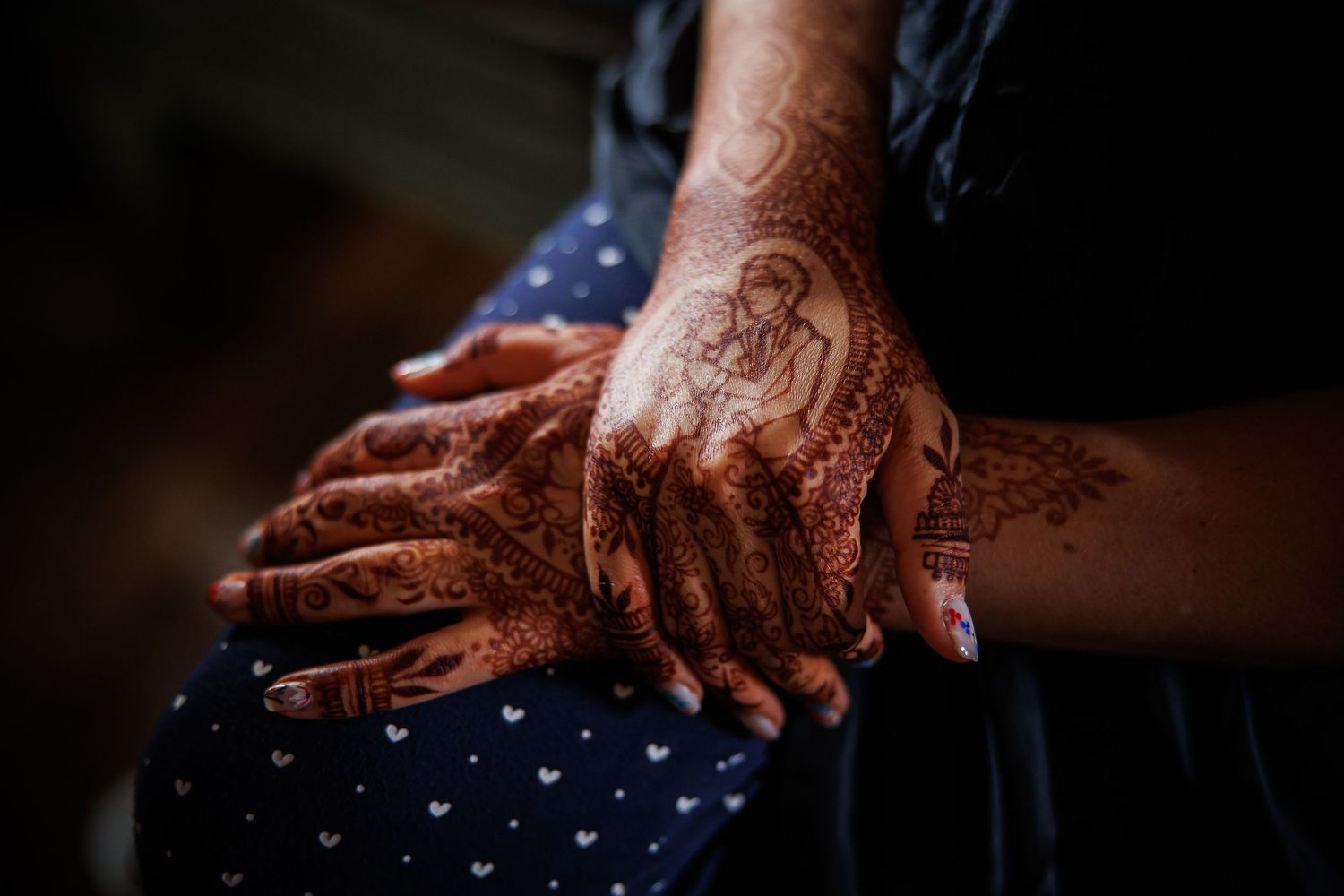 Artistic capture of hands adorned with traditional henna designs in moody lighting.