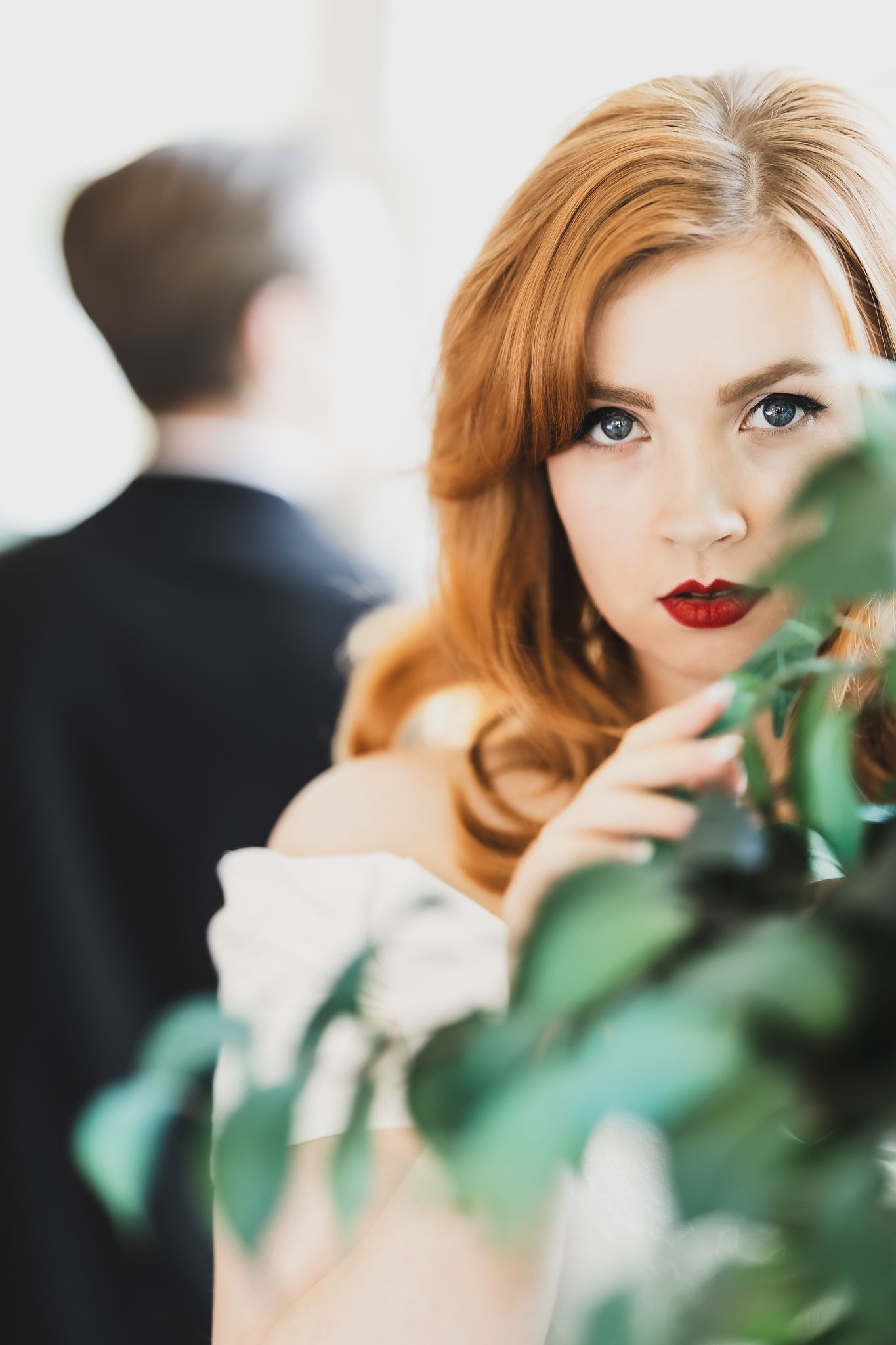Artistic wedding photo with greenery and dramatic lighting.