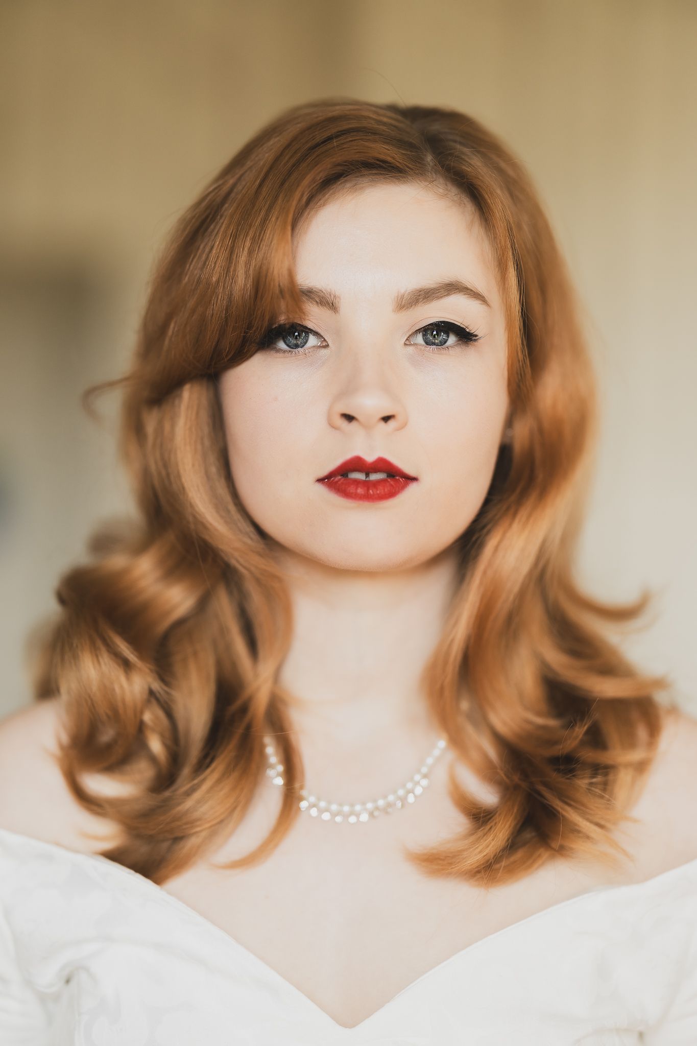 Close up beauty portrait featuring vintage waves, red lipstick and pearl necklace.