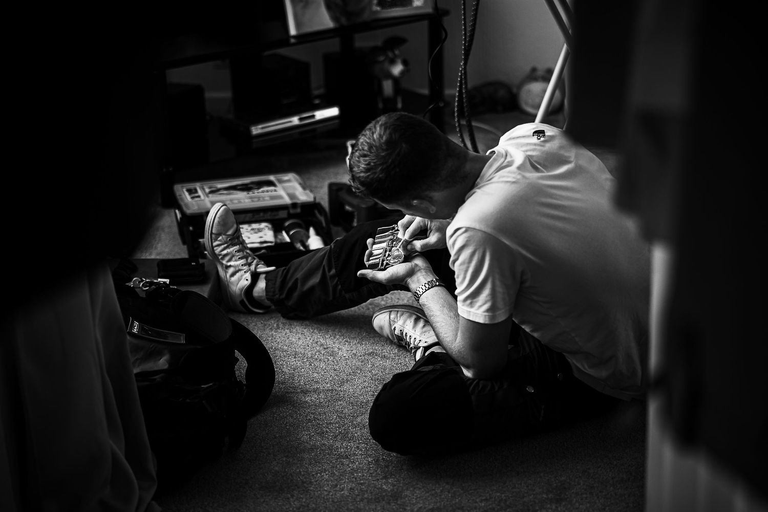 Black and white image of someone working on crafts or details in dim lighting.