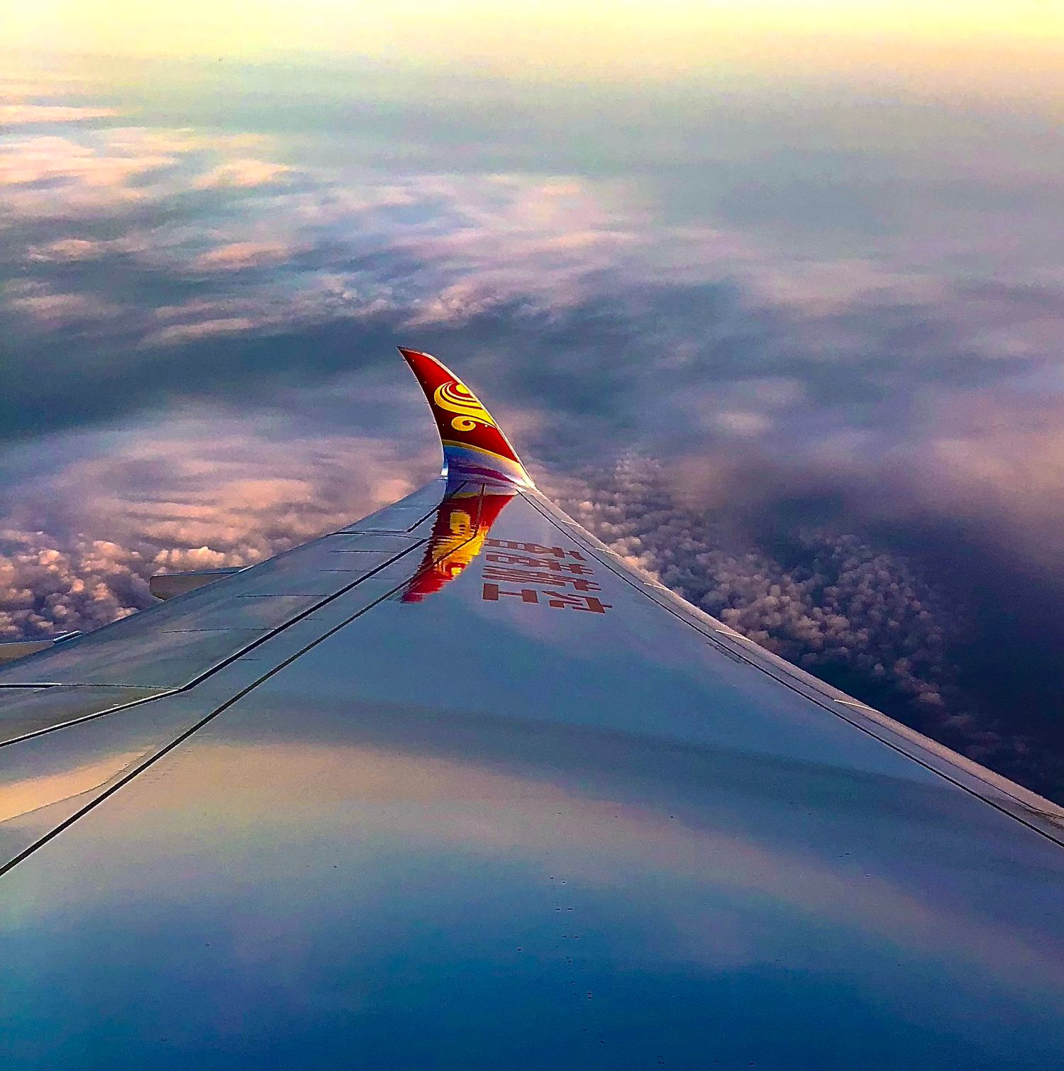 Blick aus dem Flugzeugfenster auf Wolken bei Sonnenuntergang