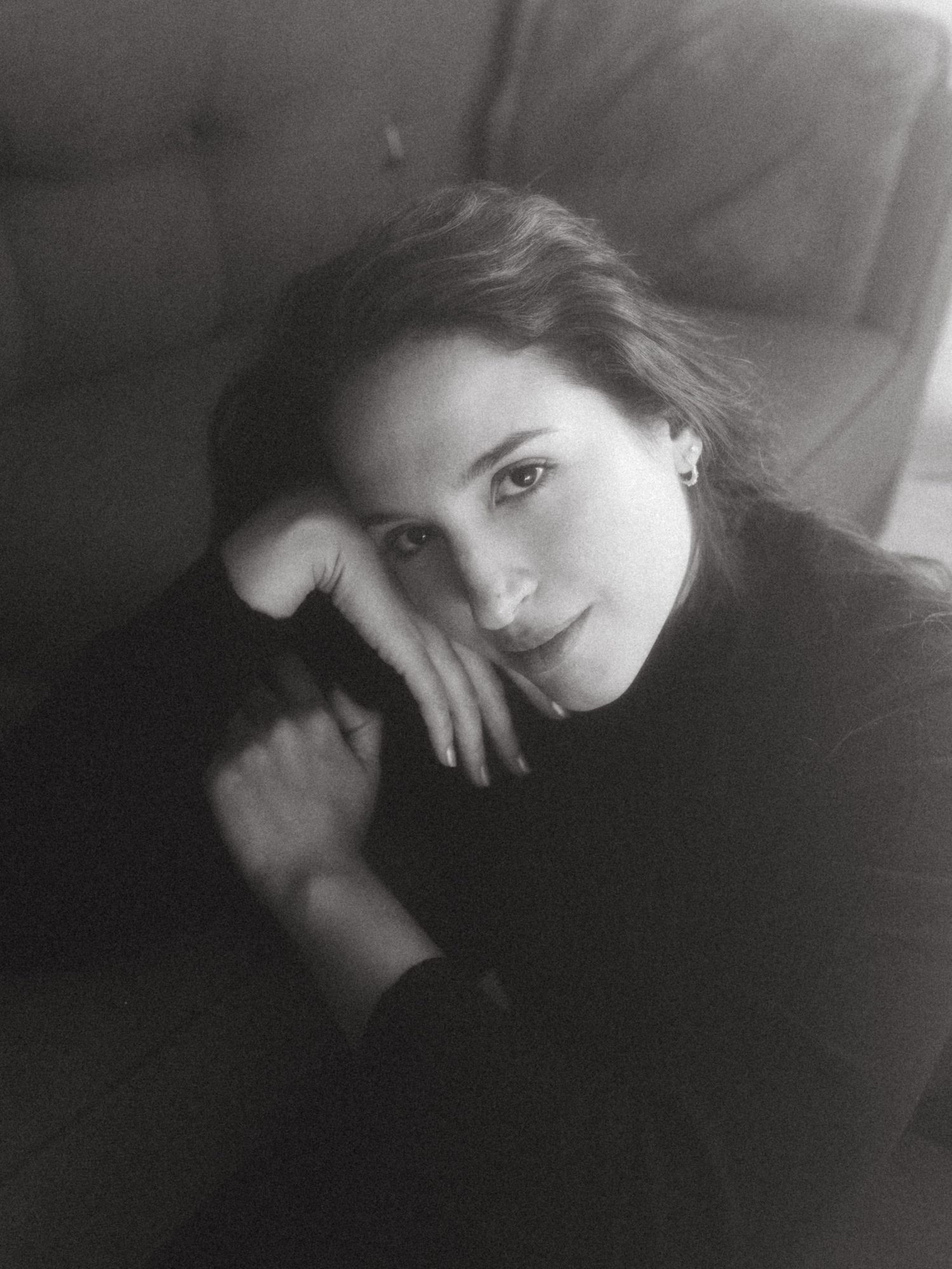 Black and white photograph of a dark haired model in a studio setting, soft contrast.