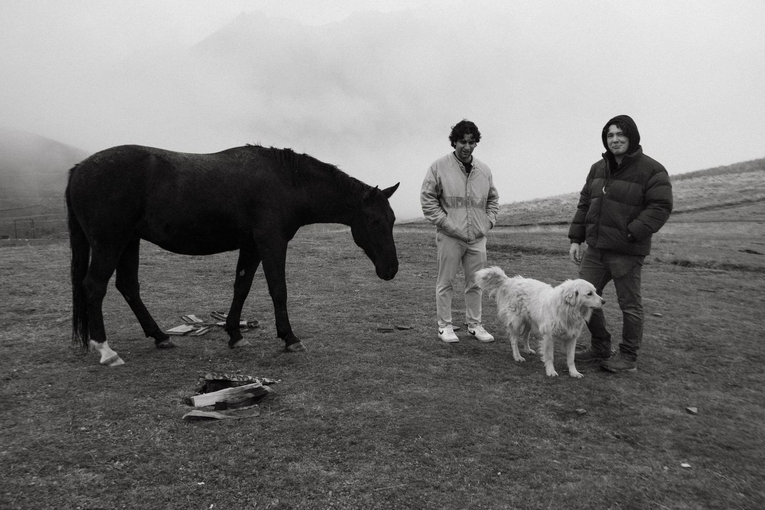 Black and white photograph of a horse, a dog and two men in Kazbegi mountains in Georgia