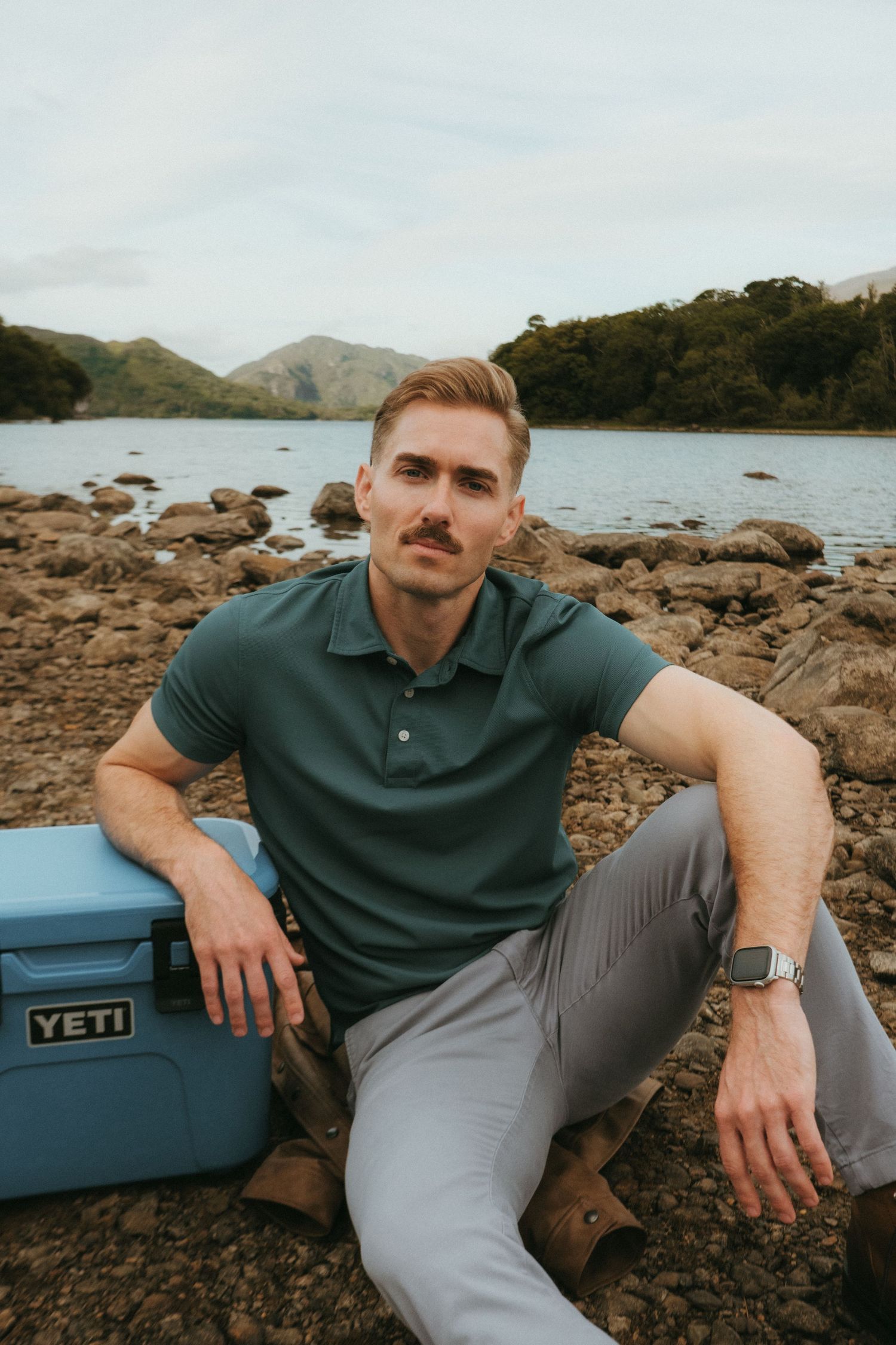 Portrait of young man in Killarney National Park, he has short blonde hair and a mustache.