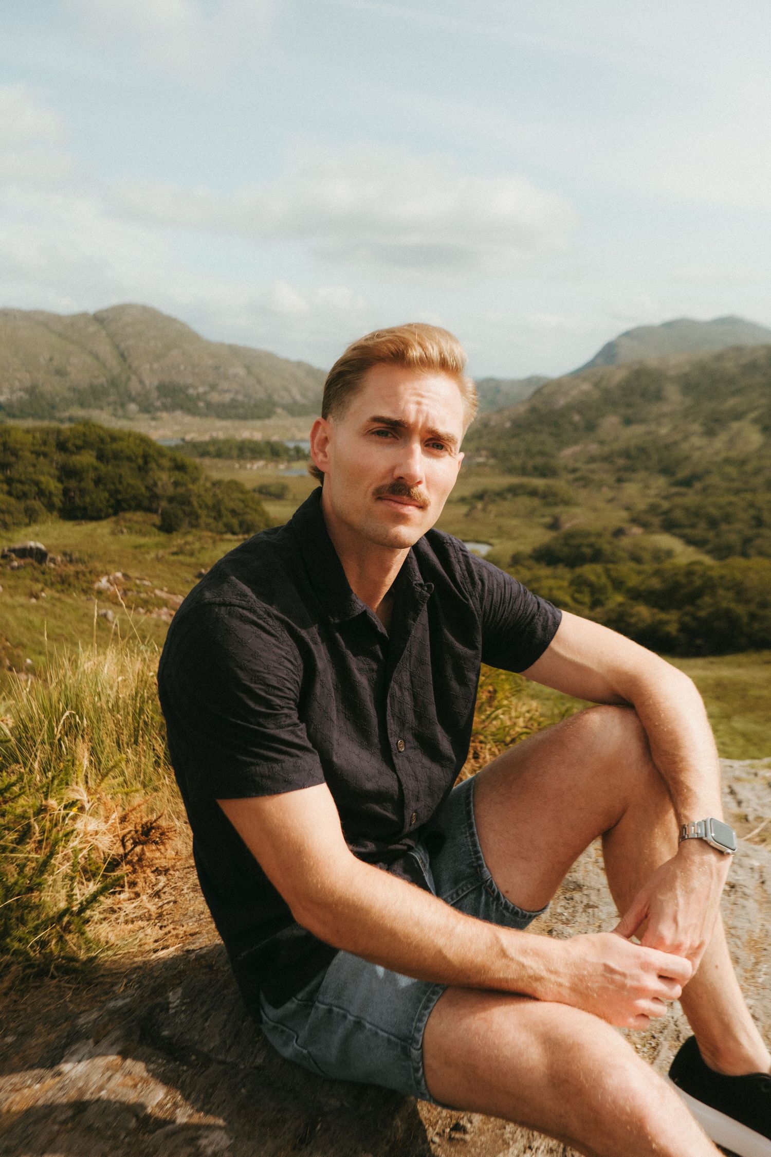 Portrait of young man in Killarney National Park, he has short blonde hair and a mustache.