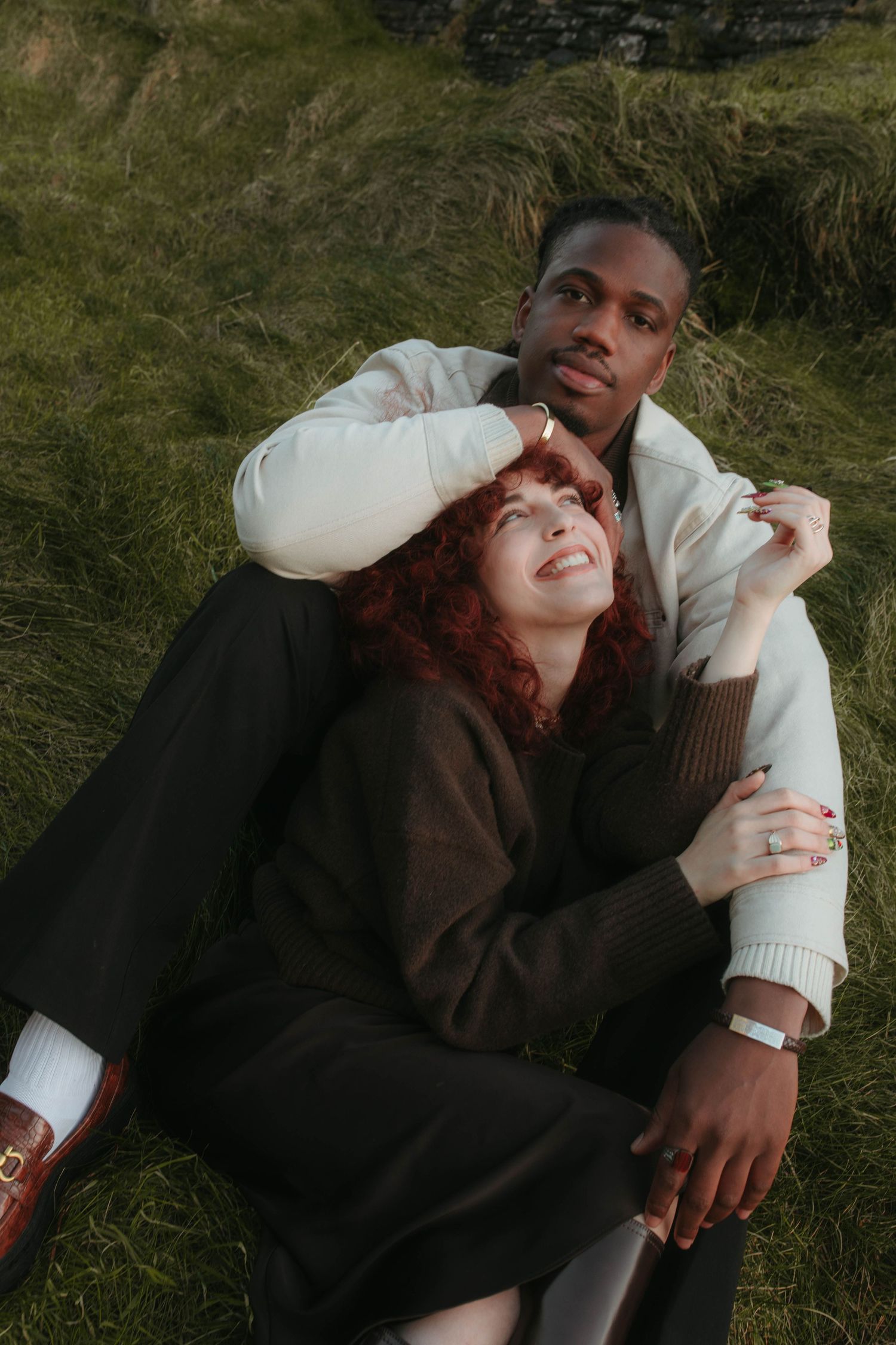 Photograph of couple laying in tall grass, she's laughing