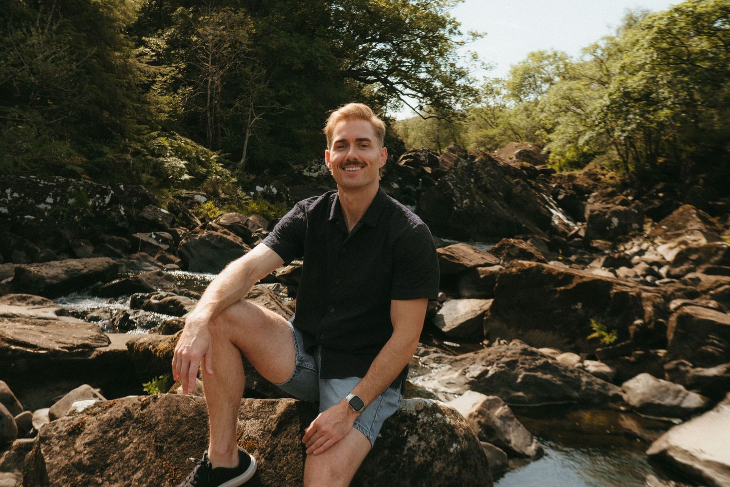 Portrait of young man in Killarney National Park, he has short blonde hair and a mustache.