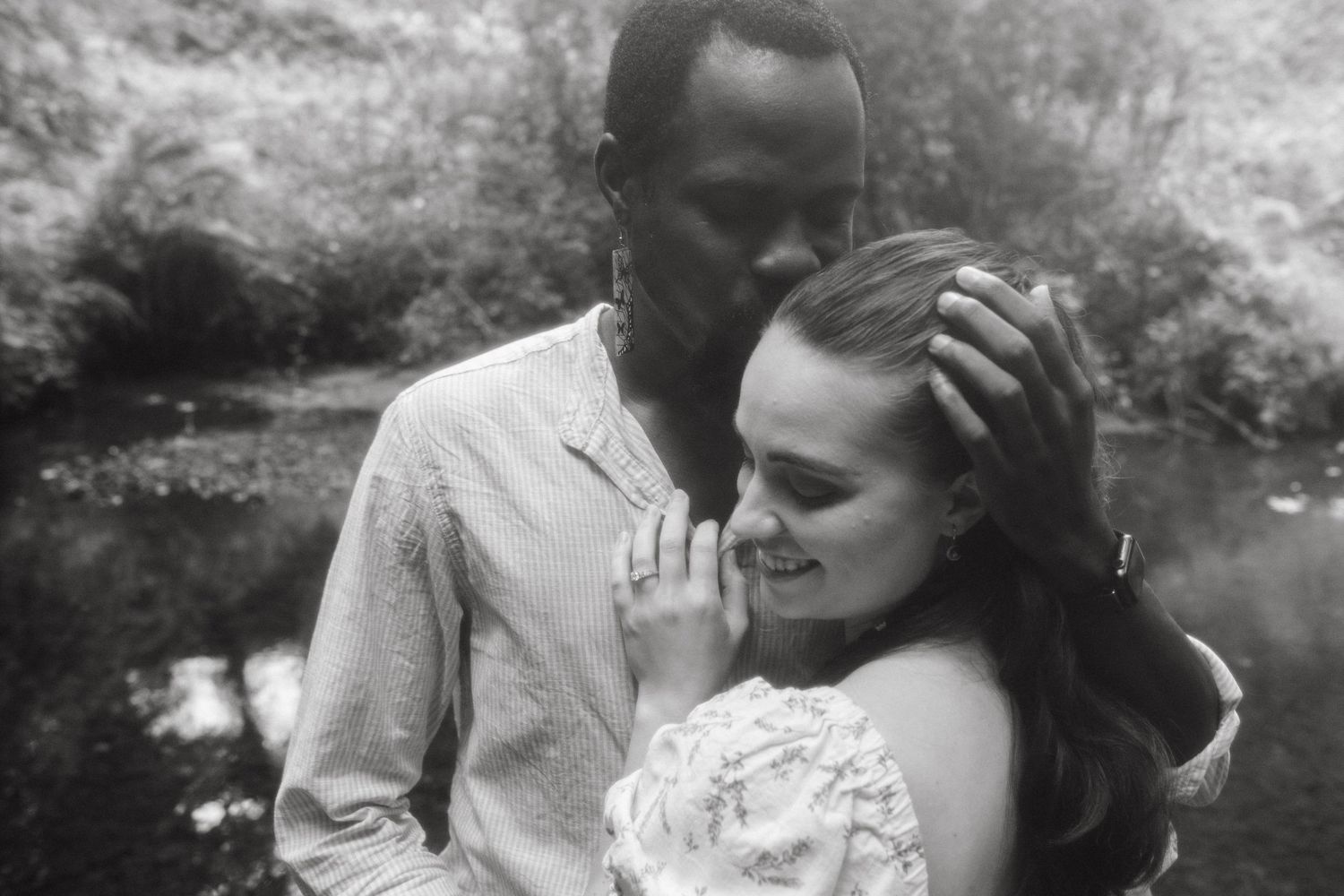 Black and white photograph of a couple, he's kissing her forehead