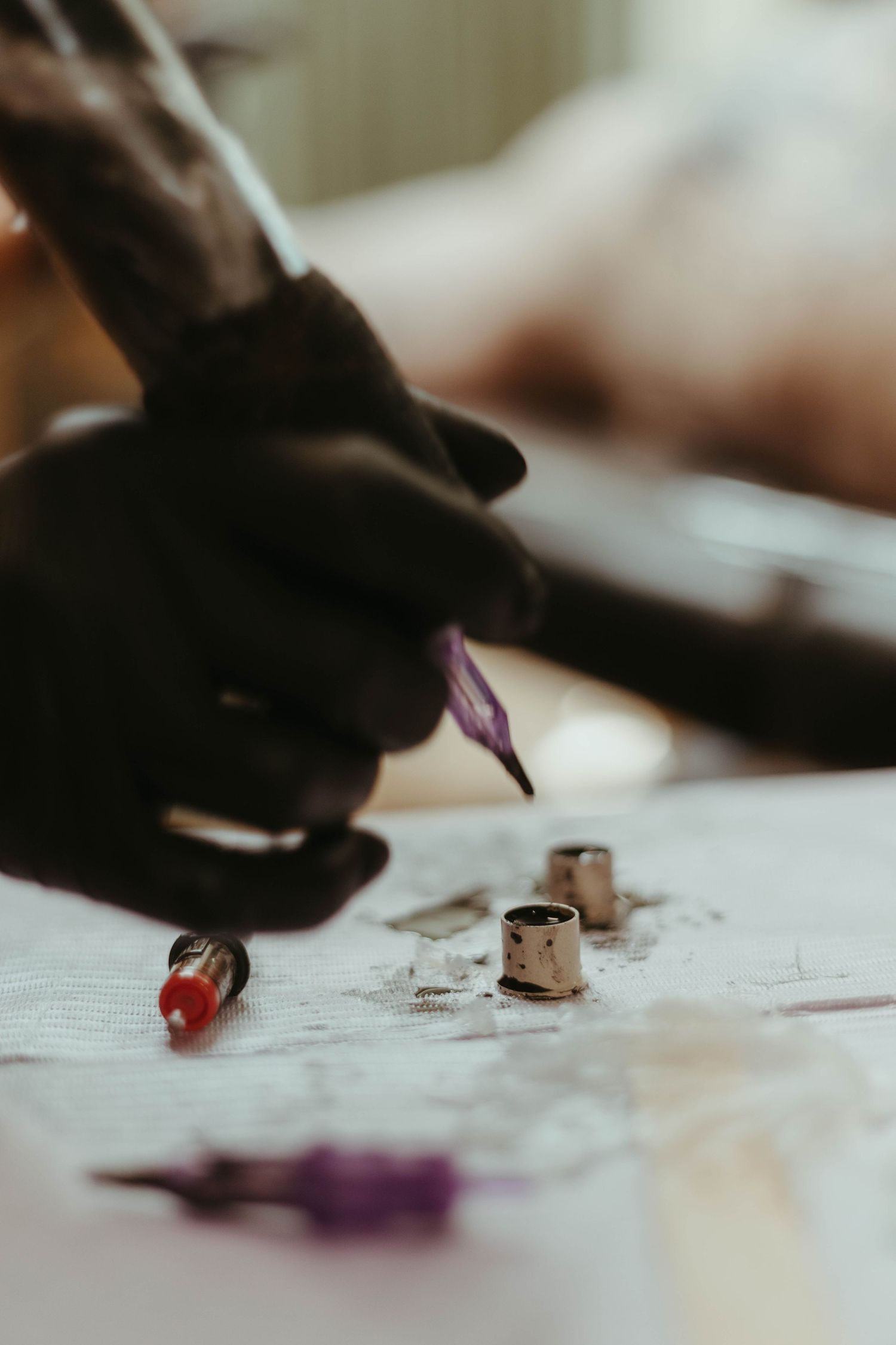 close up of a tattoo artist tattooing a client you can see her gloves and the needle