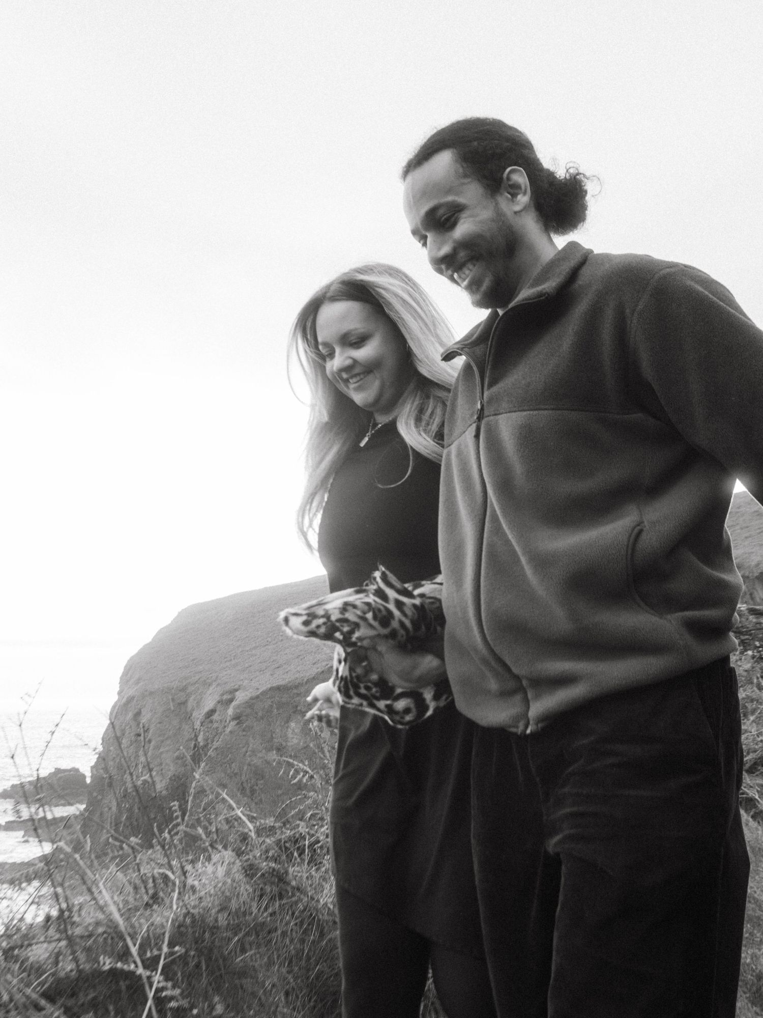Photograph of couple posing at Nohoval Cove in Cork, Ireland. Soft contrast, warm colors.