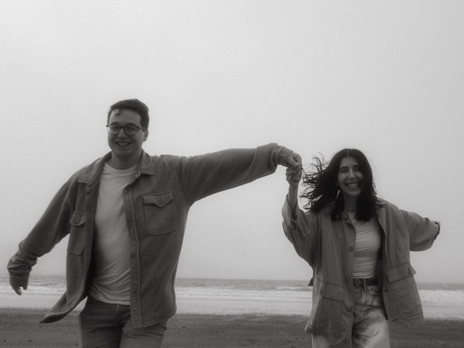 Black and white photograph of couple running at a beach