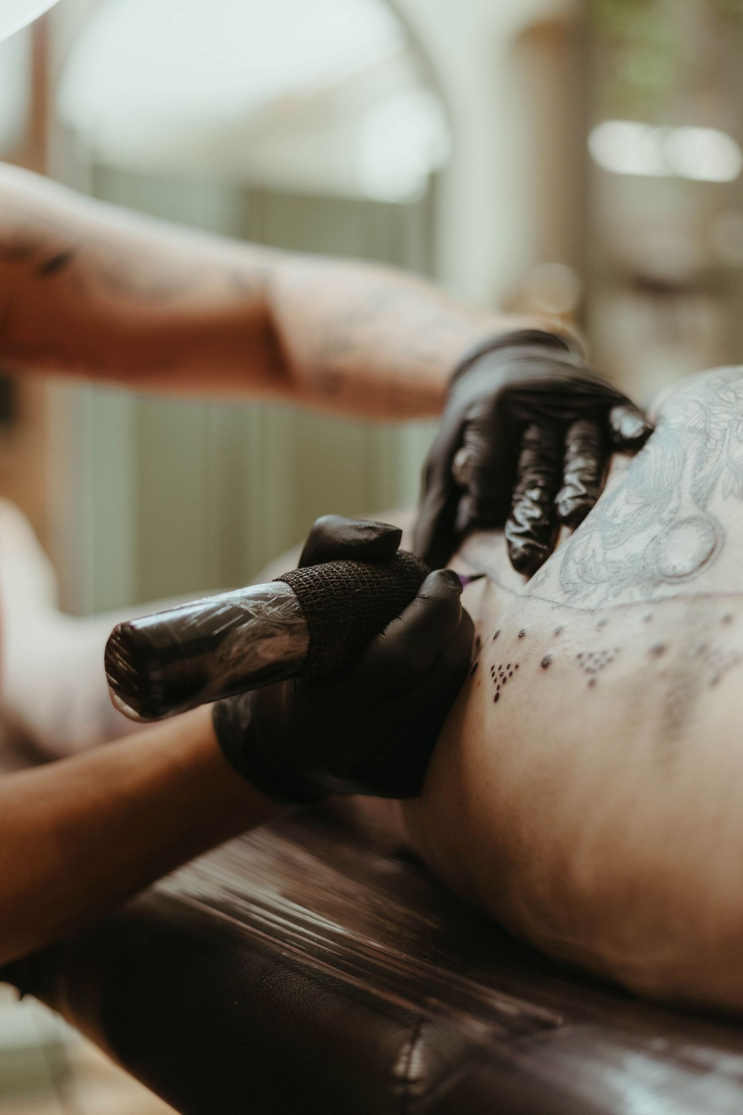 close up of a tattoo artist tattooing a client you can see her gloves and the needle