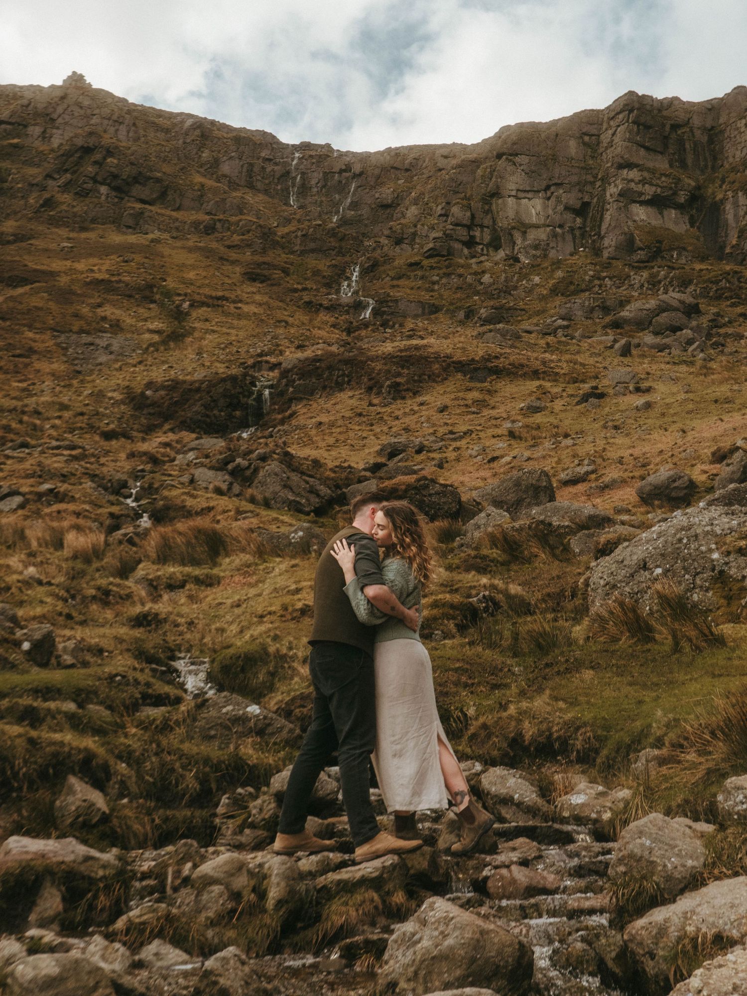 Photograph of Irish couple during their engagement session at Mahon Falls, Waterford. They are hugging in front of rugged nature.